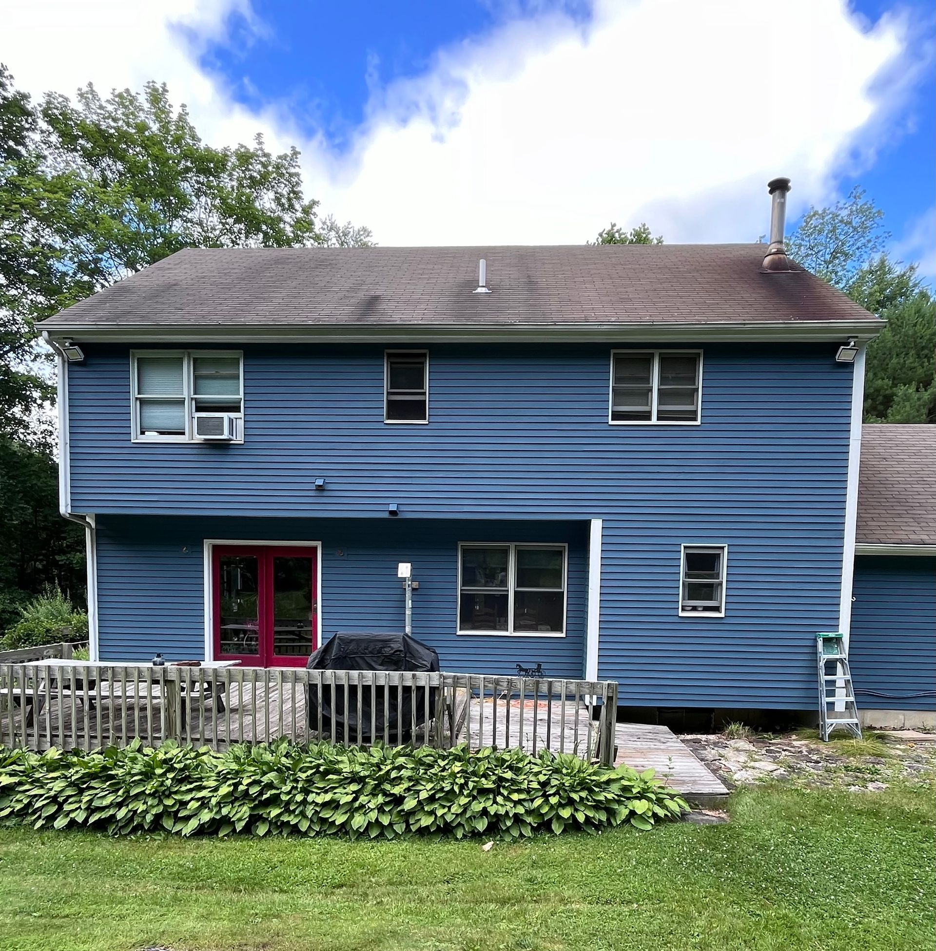 A blue house with a brown roof and a red door