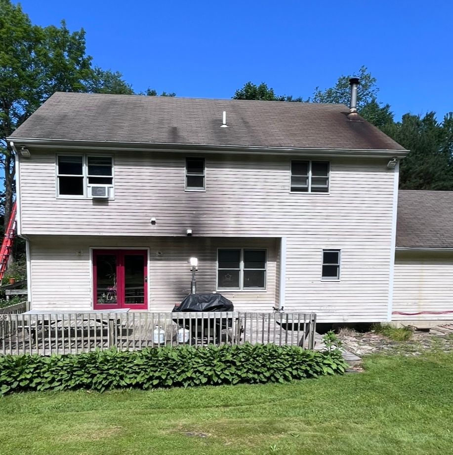 A white house with a brown roof and a red door