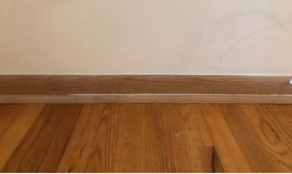 A wooden floor with a white wall behind it.