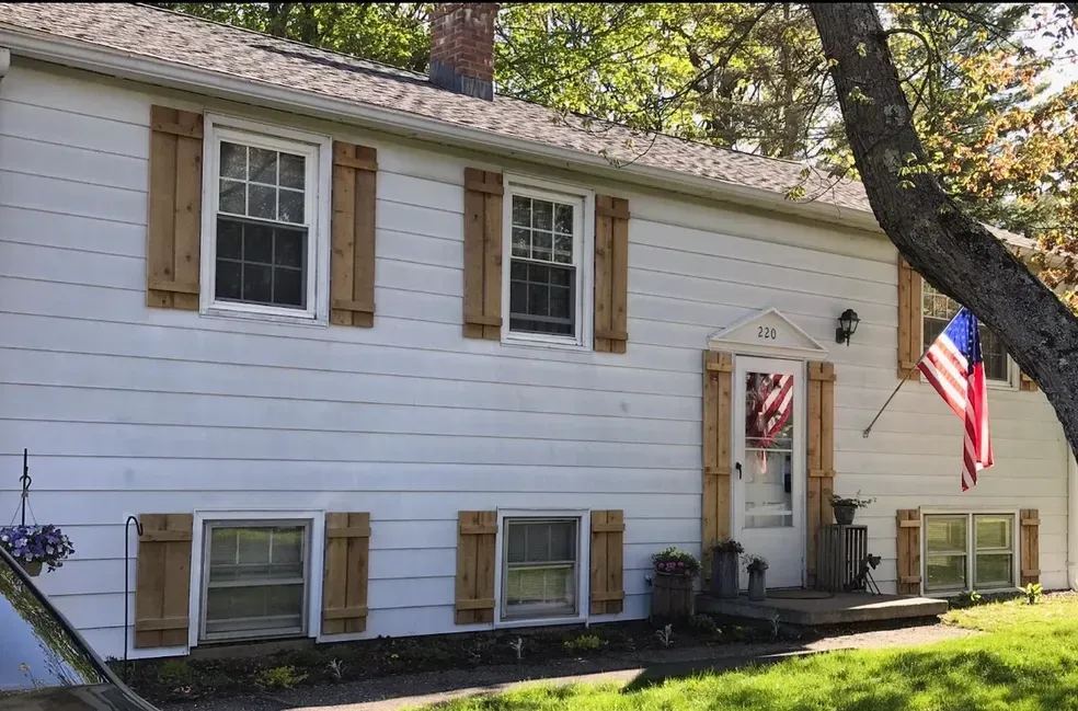 A white house with wooden shutters and an american flag