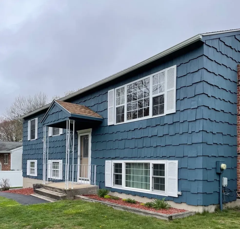 A blue house with white shutters on the windows