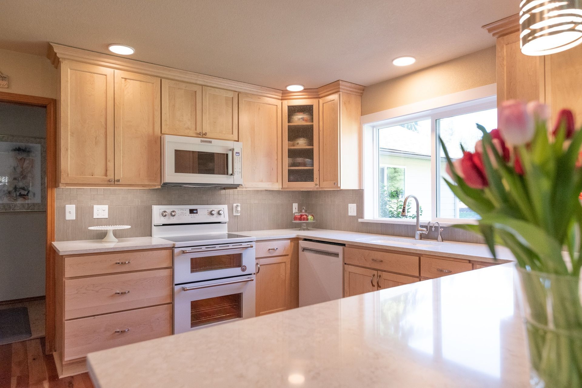 A kitchen with a vase of flowers on the counter.