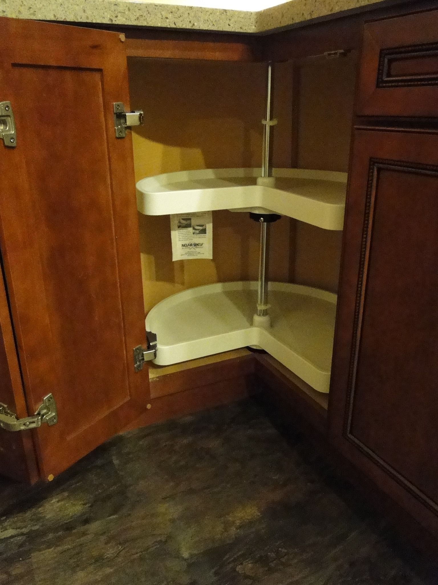 A kitchen cabinet with a round shelf inside of it.