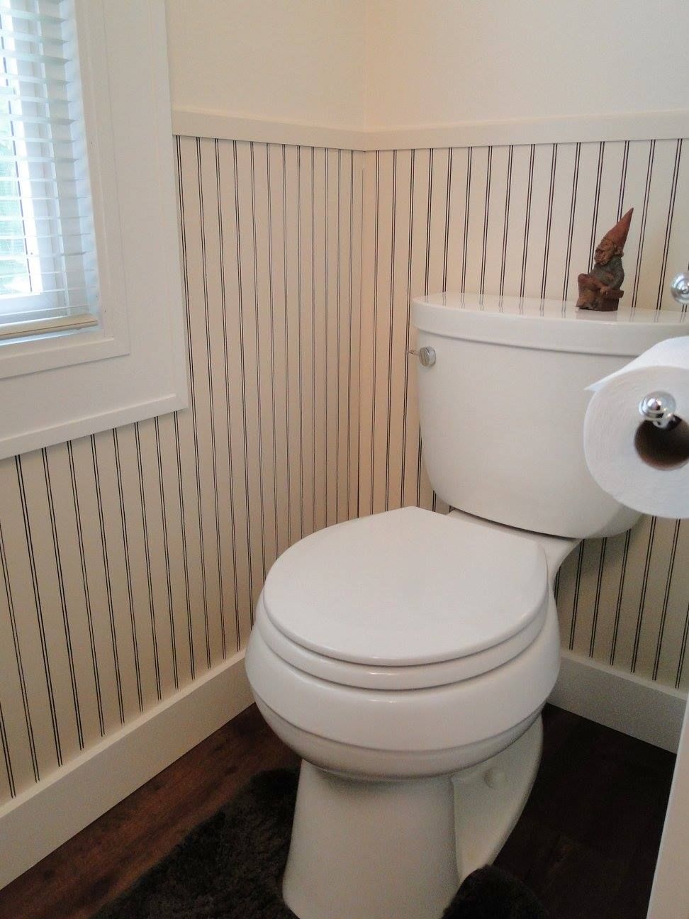 A toilet in a bathroom next to a window