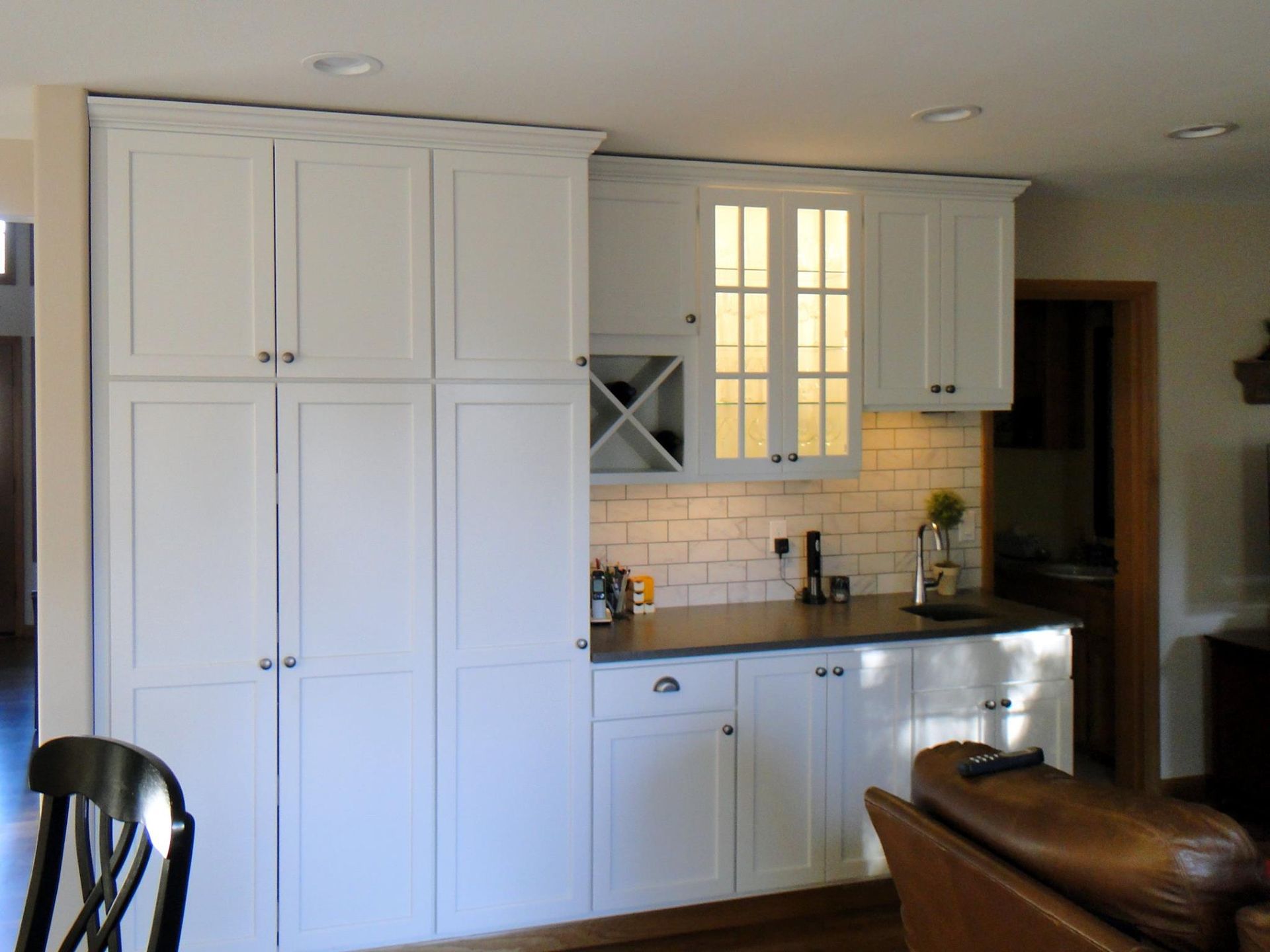 A kitchen with white cabinets and a wine rack