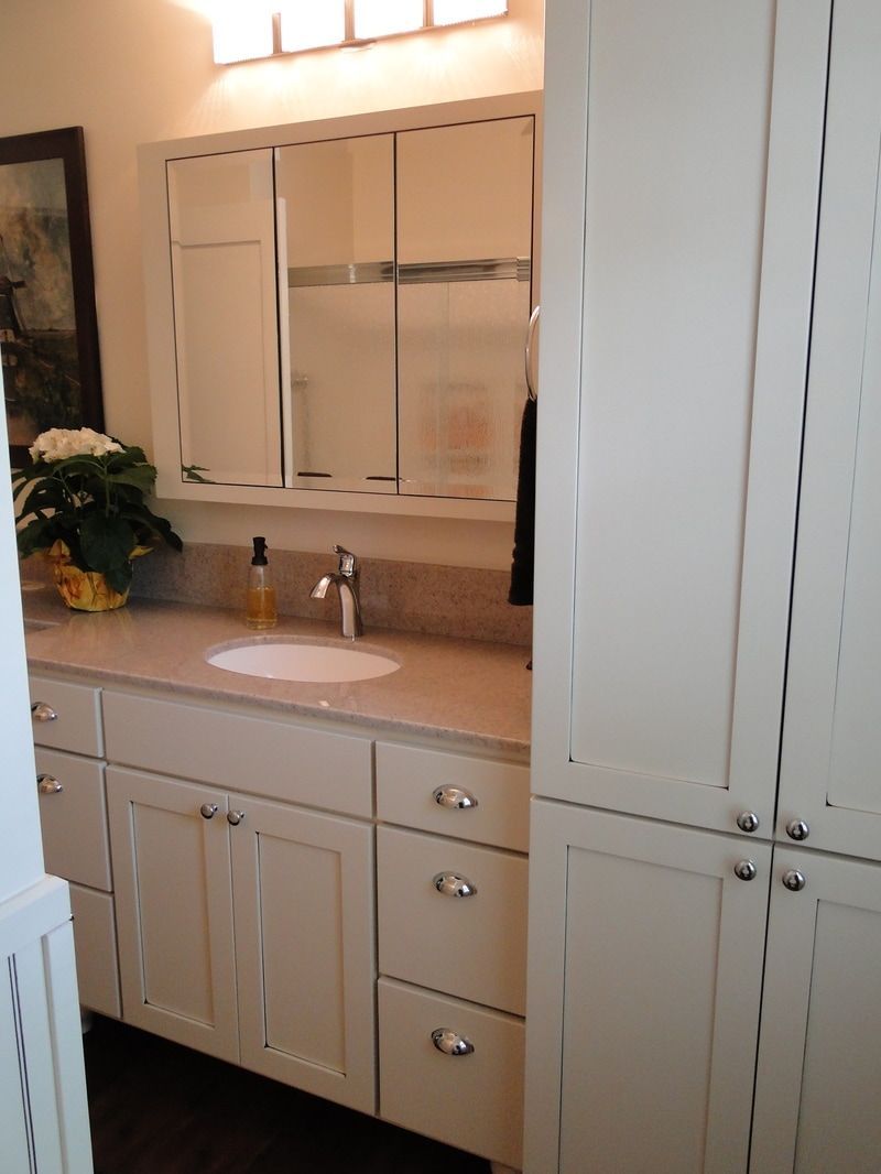 A bathroom with white cabinets and a sink