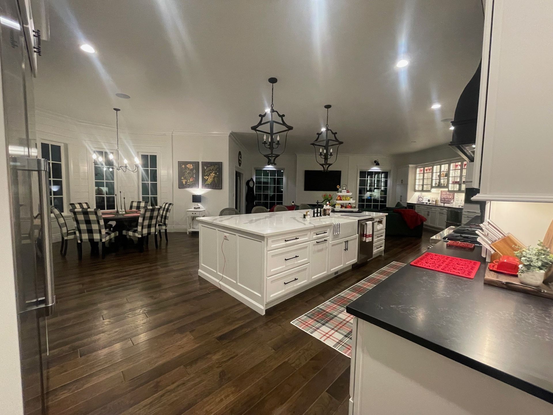 Spacious kitchen with a large island, dark wood floors, dining area, and decorative lighting.