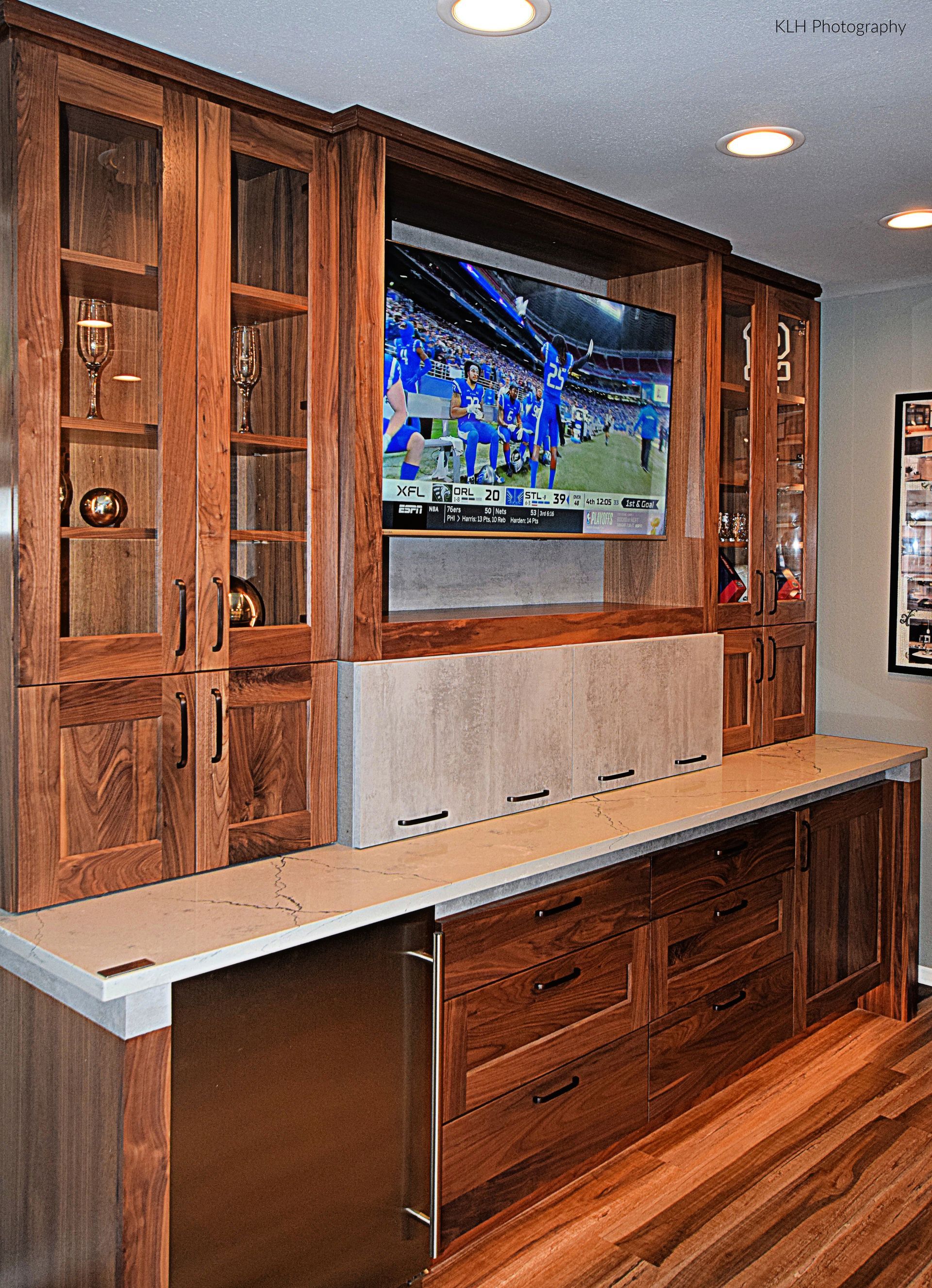 A kitchen with wooden cabinets and a flat screen tv