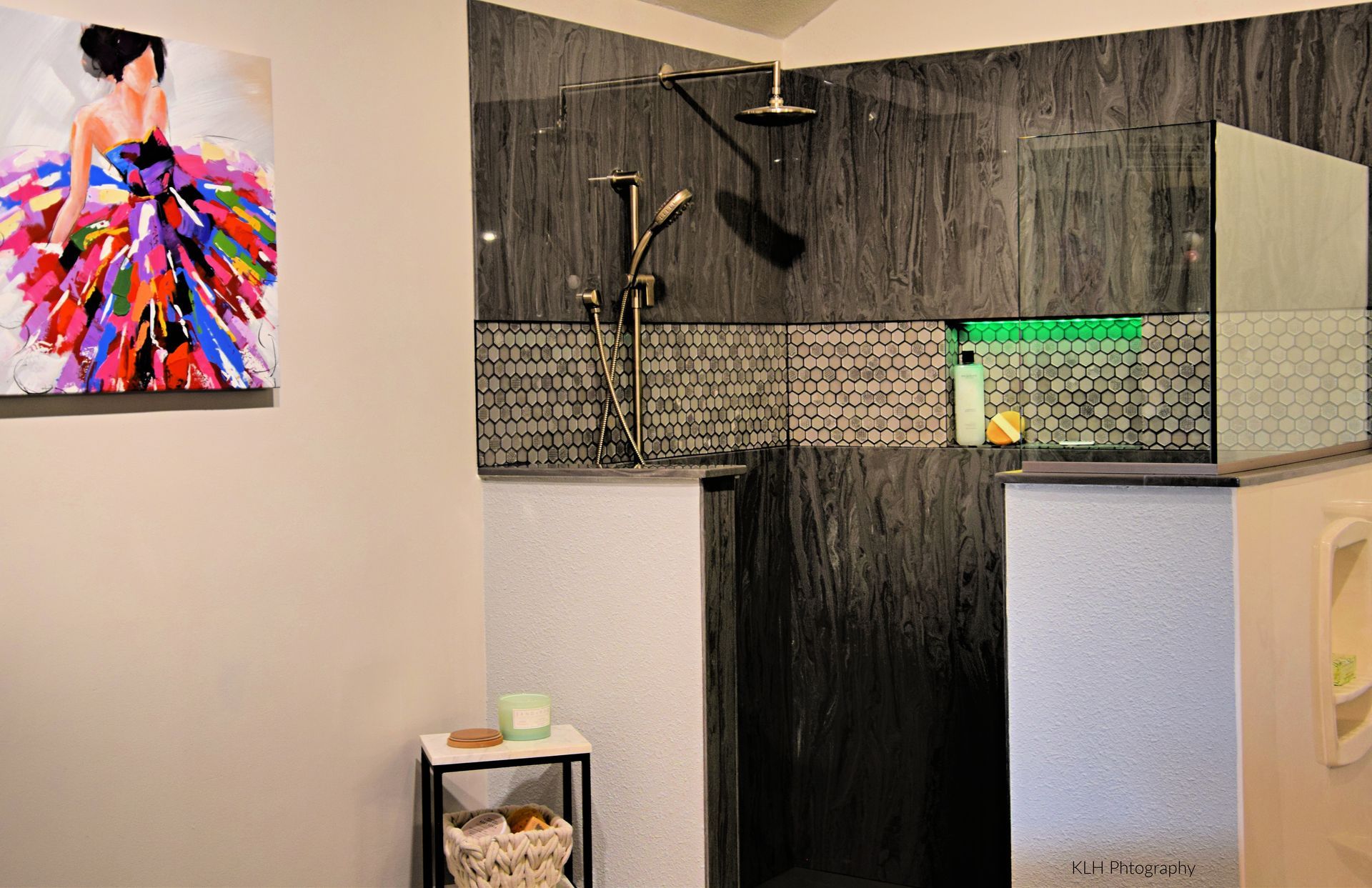 A bathroom with a walk in shower and a painting on the wall.