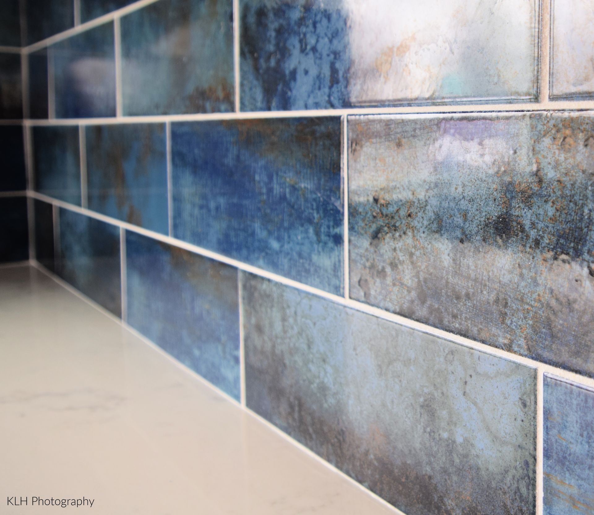 A close up of a blue tile wall with white grout.