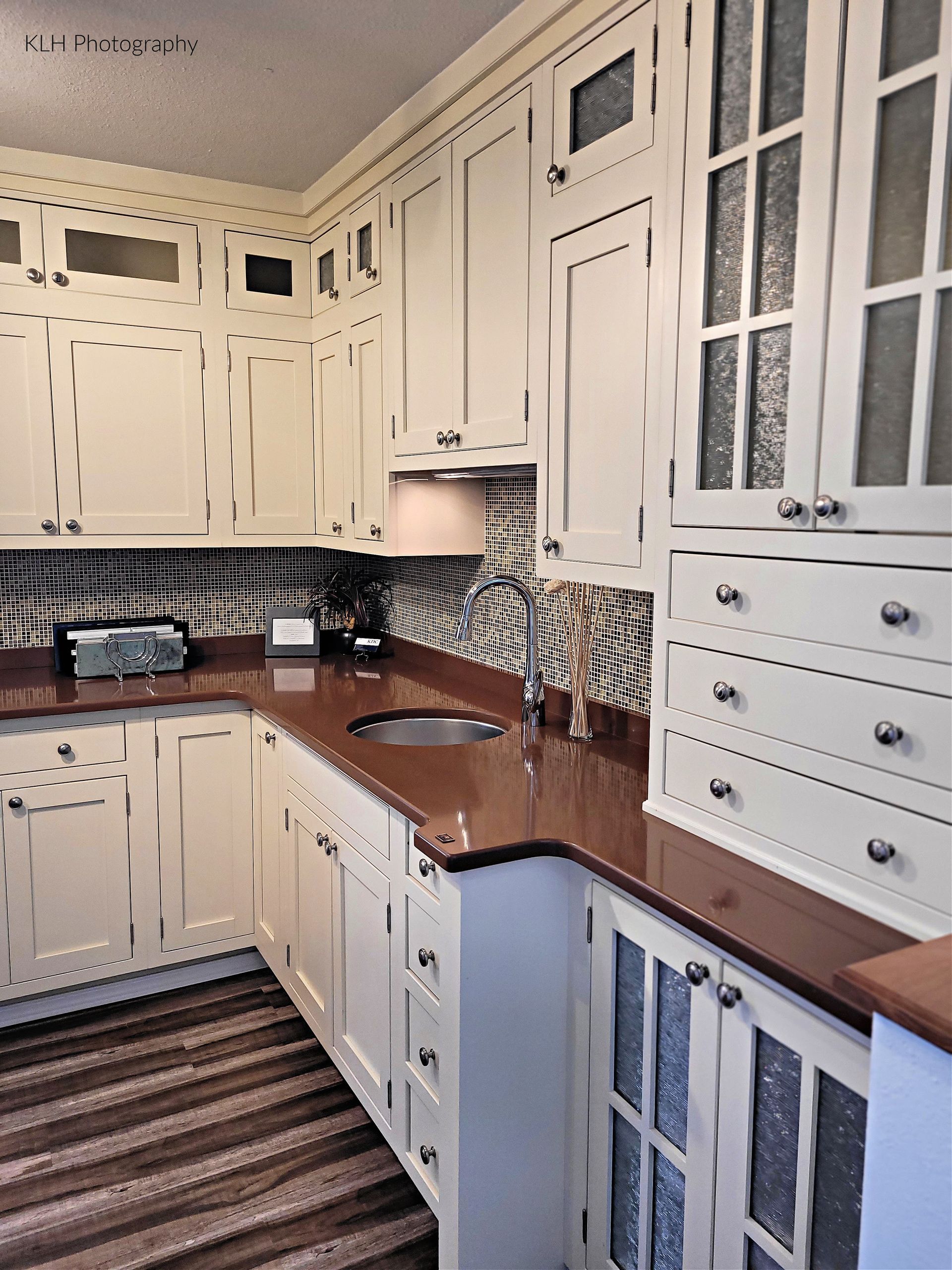 A kitchen with white cabinets and brown counter tops