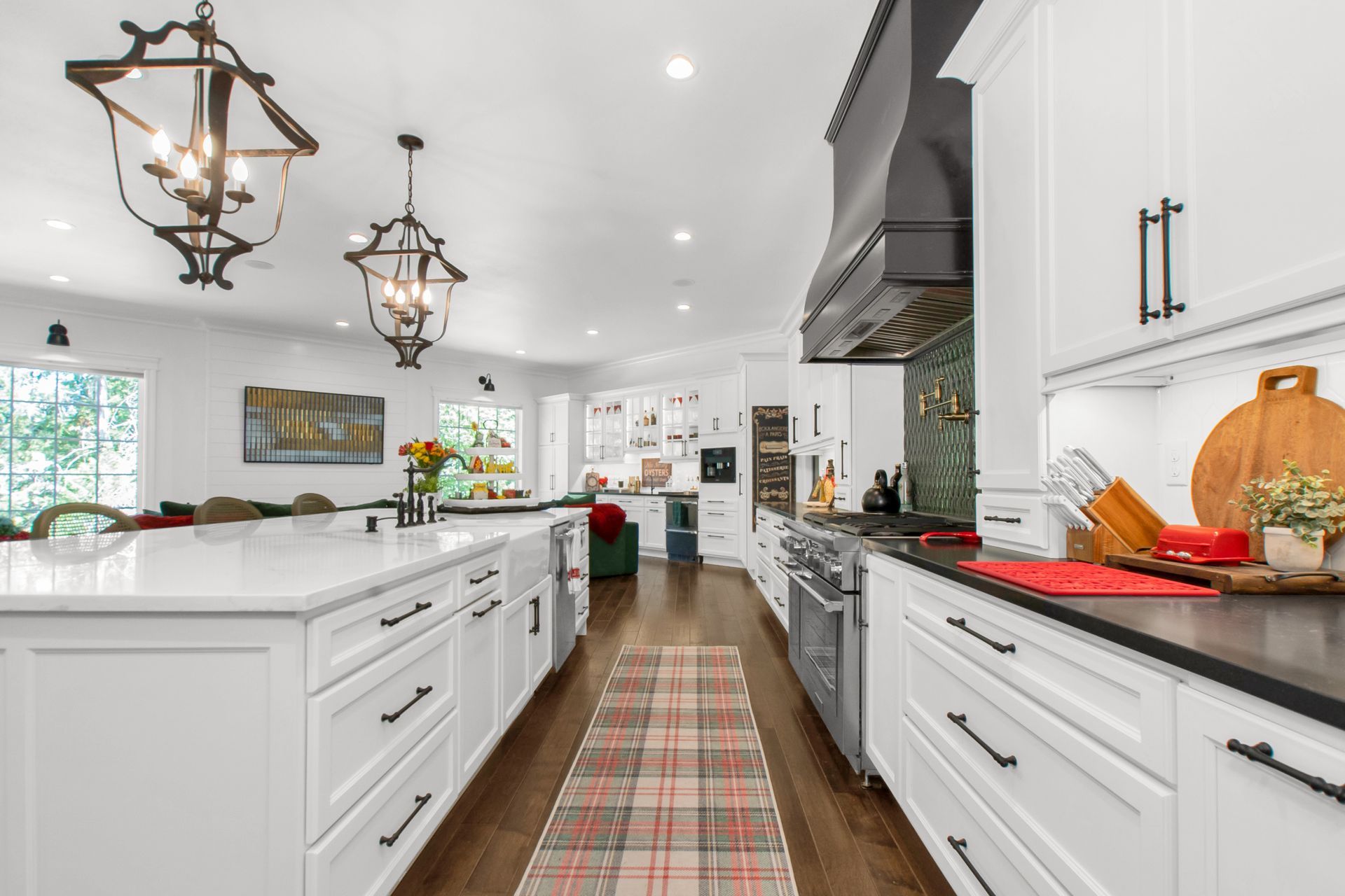A kitchen with white cabinets , stainless steel appliances , and a plaid rug.