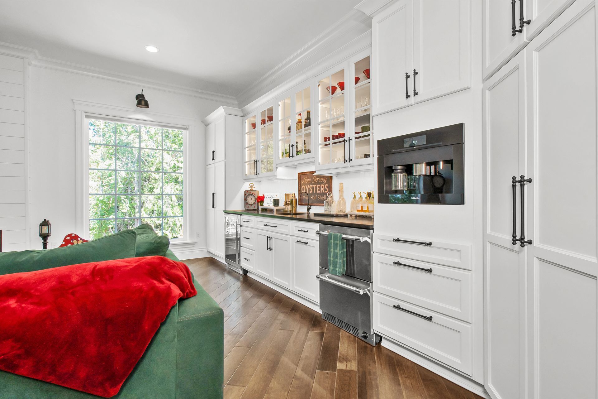A living room with a green couch and a red blanket on the couch.