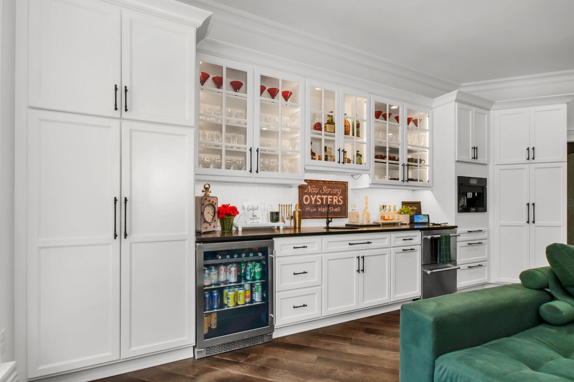 A kitchen with white cabinets and a green couch.