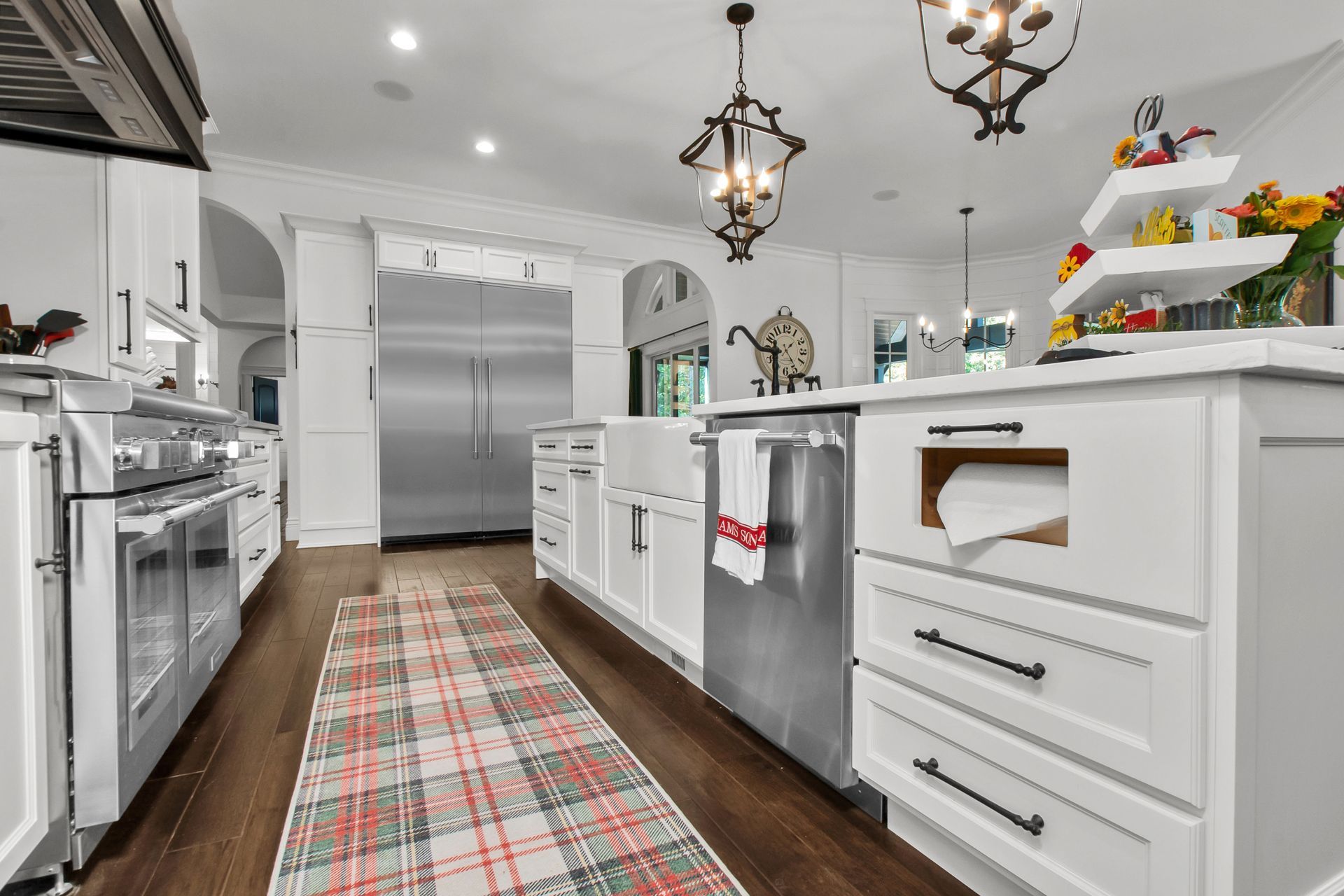 A kitchen with white cabinets , stainless steel appliances , and a plaid rug.