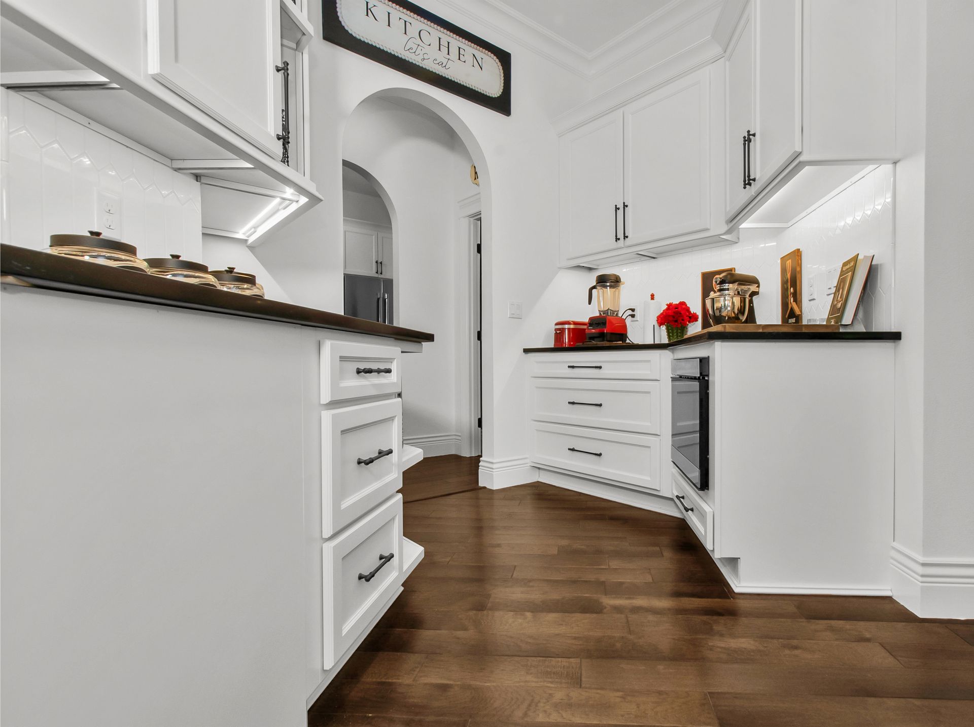 A kitchen with white cabinets and a wooden floor.