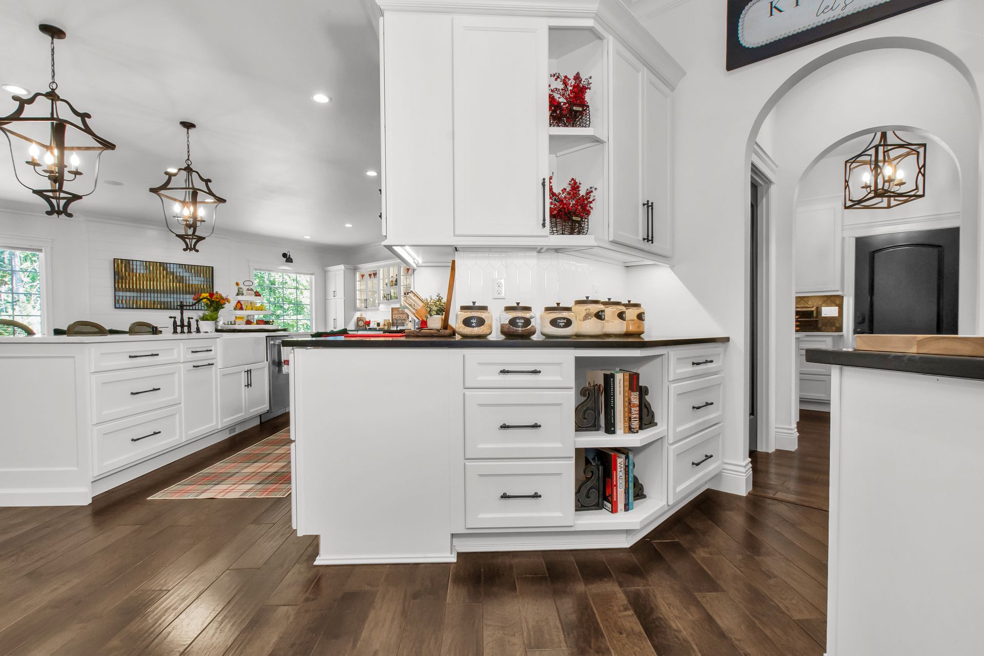 A kitchen with white cabinets and hardwood floors and a large island.
