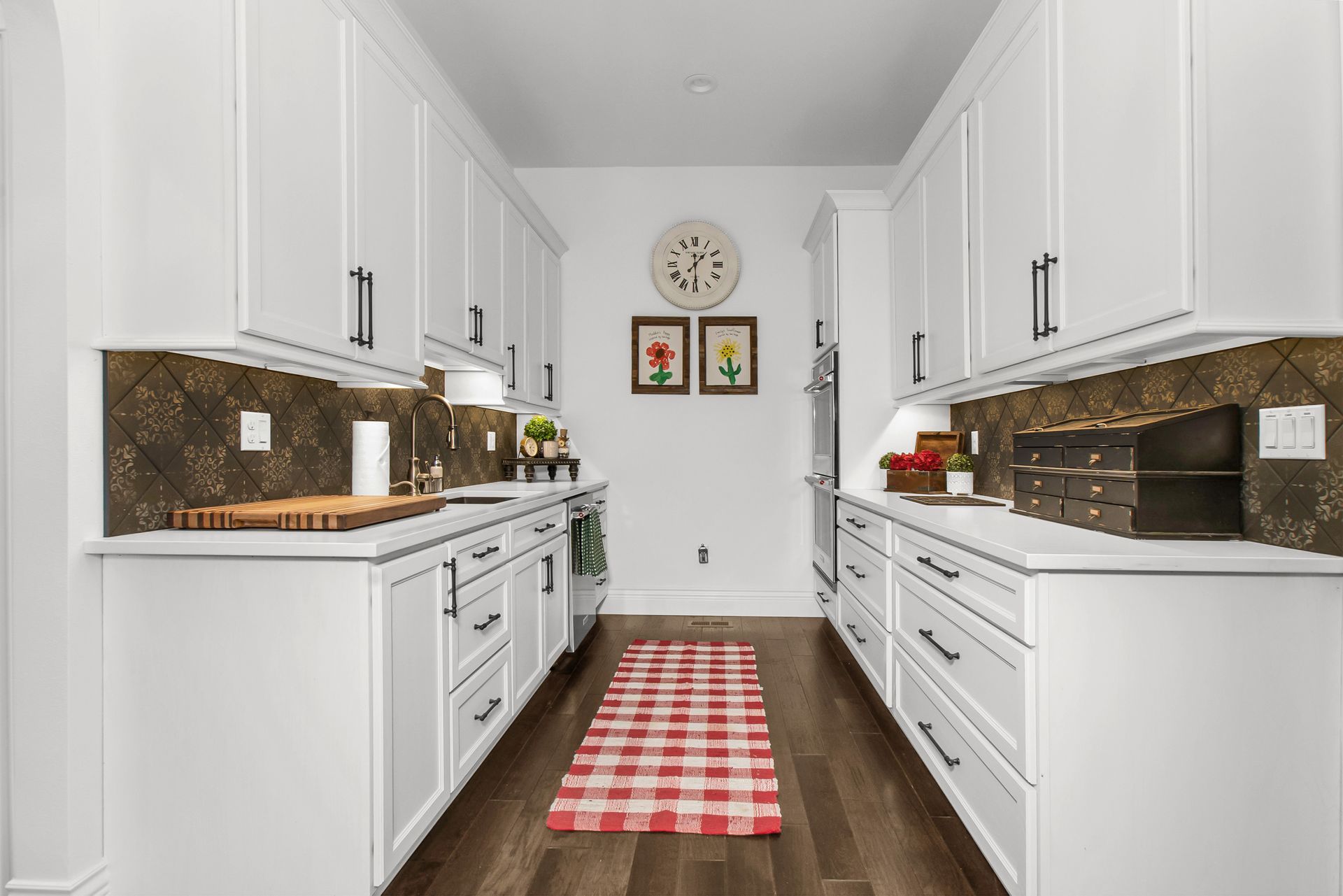 A kitchen with white cabinets and a red and white checkered rug.