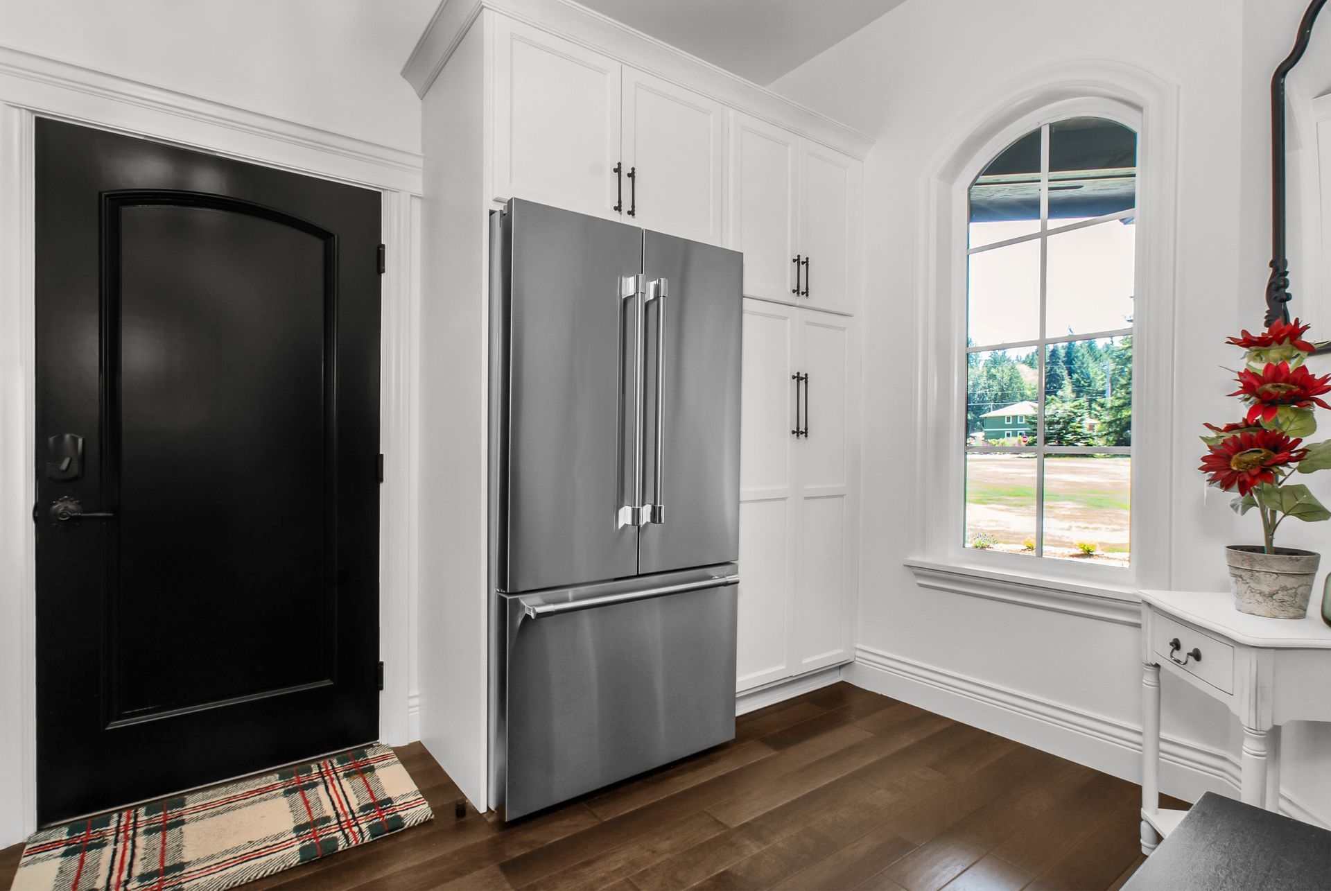 A kitchen with a stainless steel refrigerator and a black door.