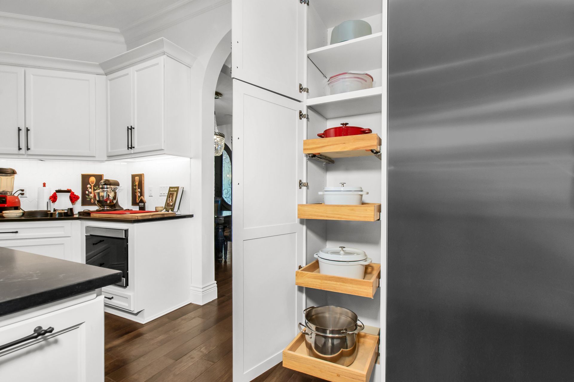 A kitchen with white cabinets , stainless steel appliances , and a pantry.