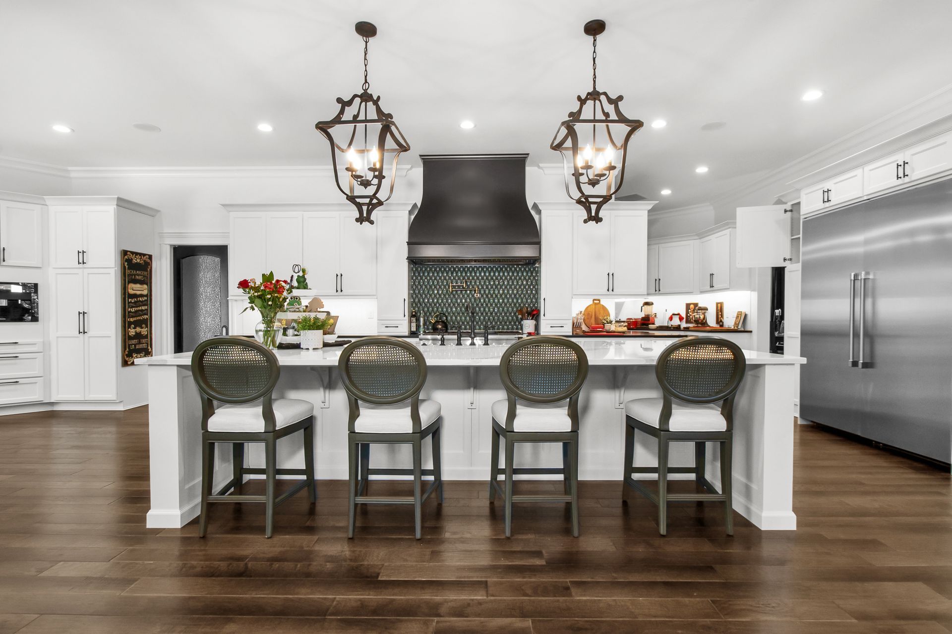 A kitchen with white cabinets , stainless steel appliances , hardwood floors and a large island.