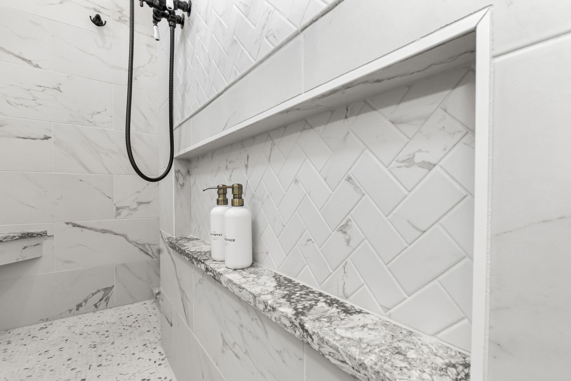A bathroom with a shower , soap dispensers , and a shelf.