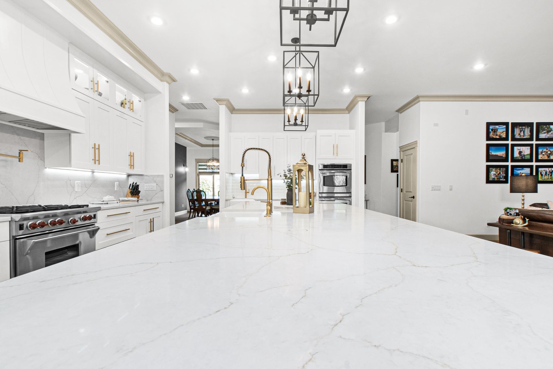 A kitchen with white cabinets , a large island , a sink , and a stove.