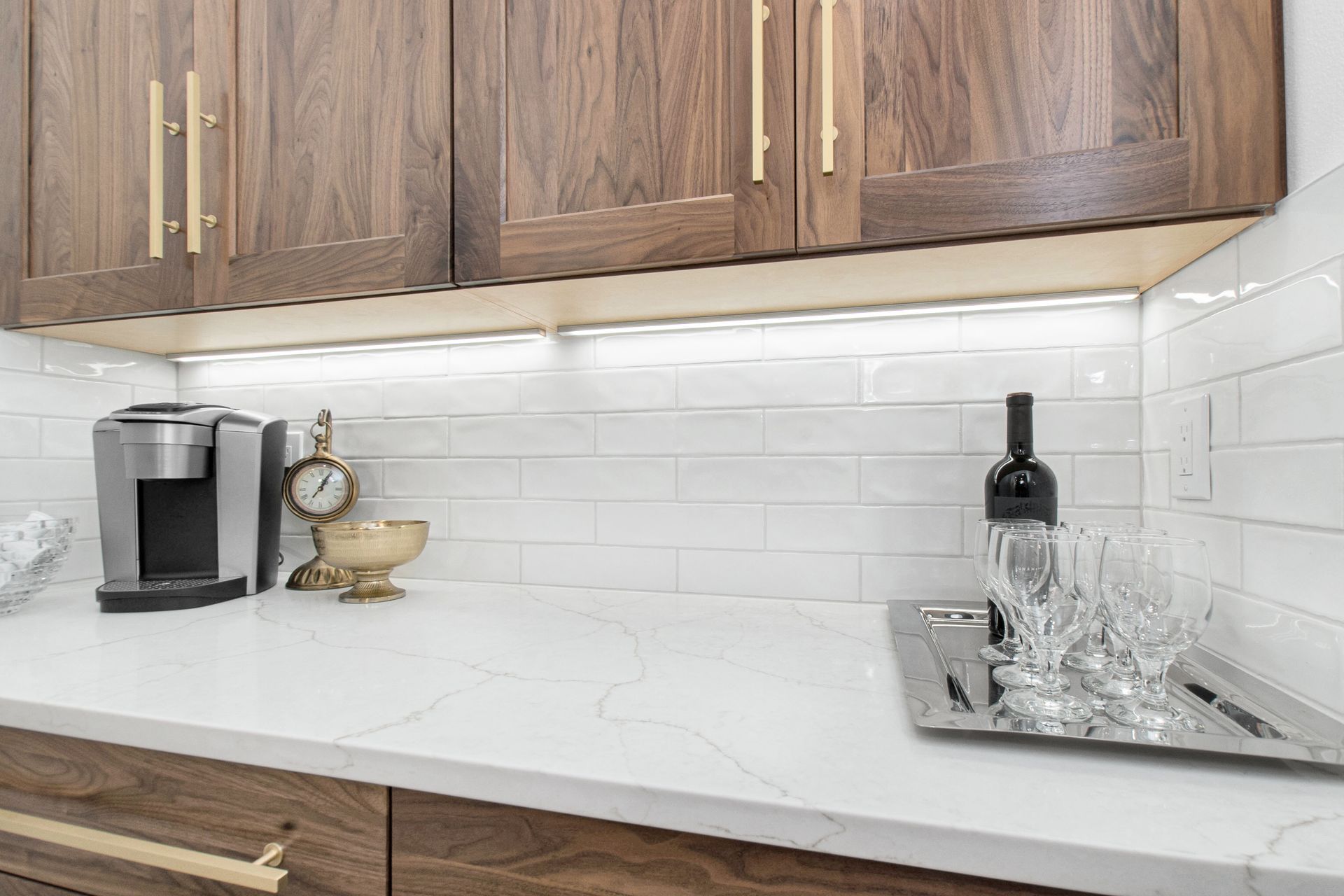 A kitchen counter with a bottle of wine and glasses on it.