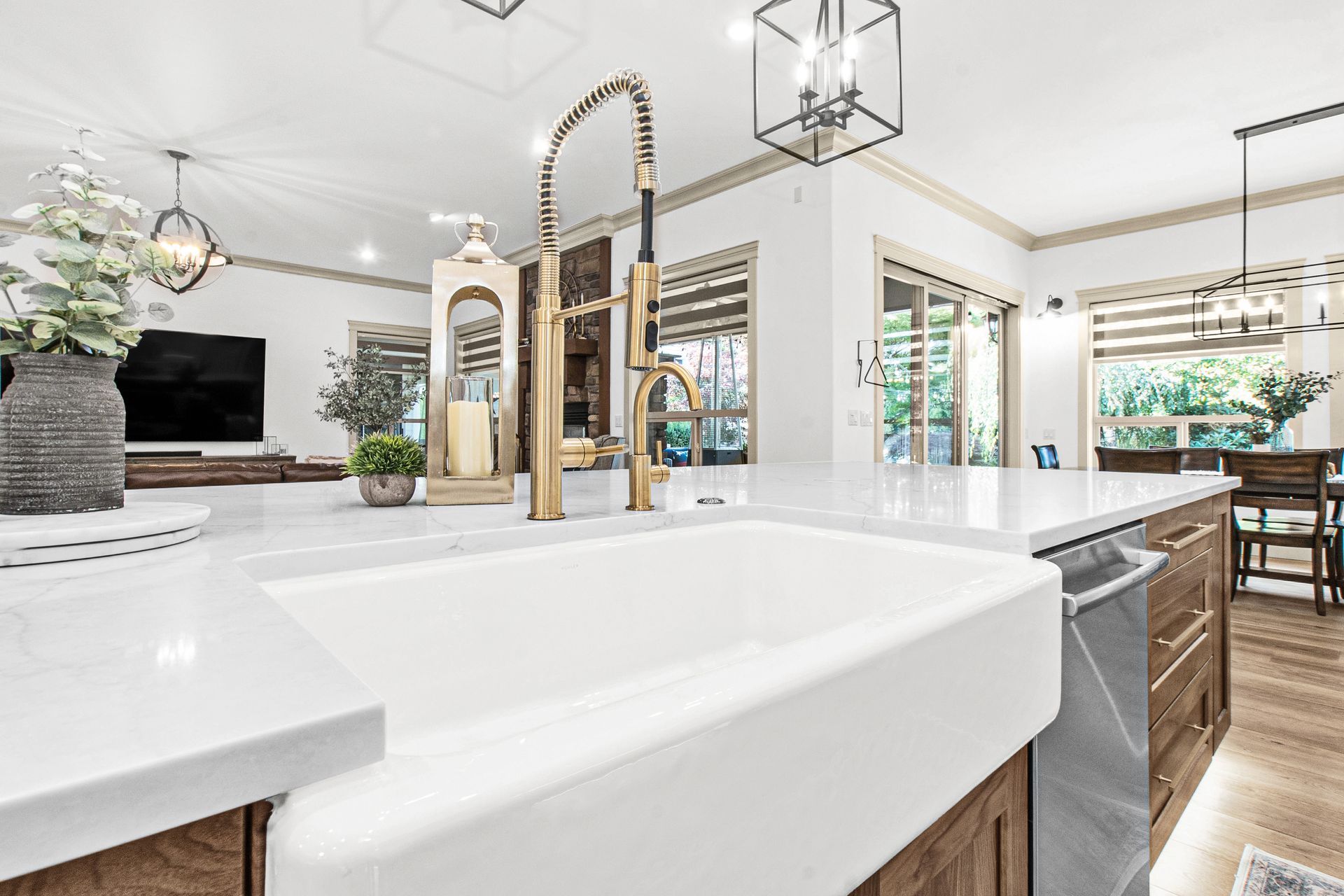 A kitchen with a large white sink and a brass faucet.