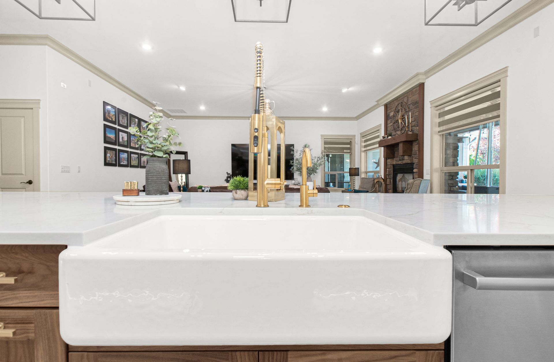 A kitchen with a white sink and a brass faucet.