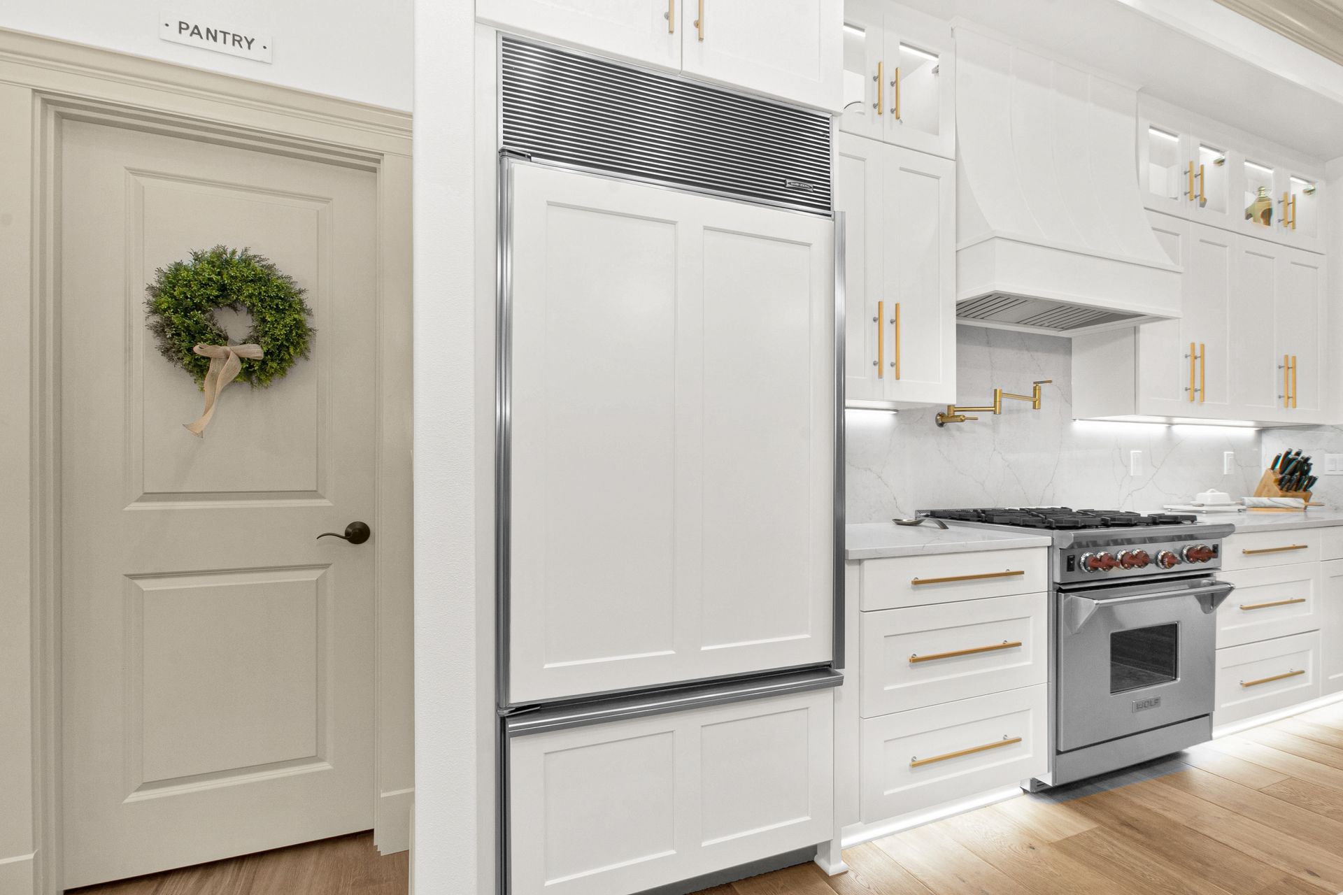 A kitchen with white cabinets , stainless steel appliances , a stove and a refrigerator.