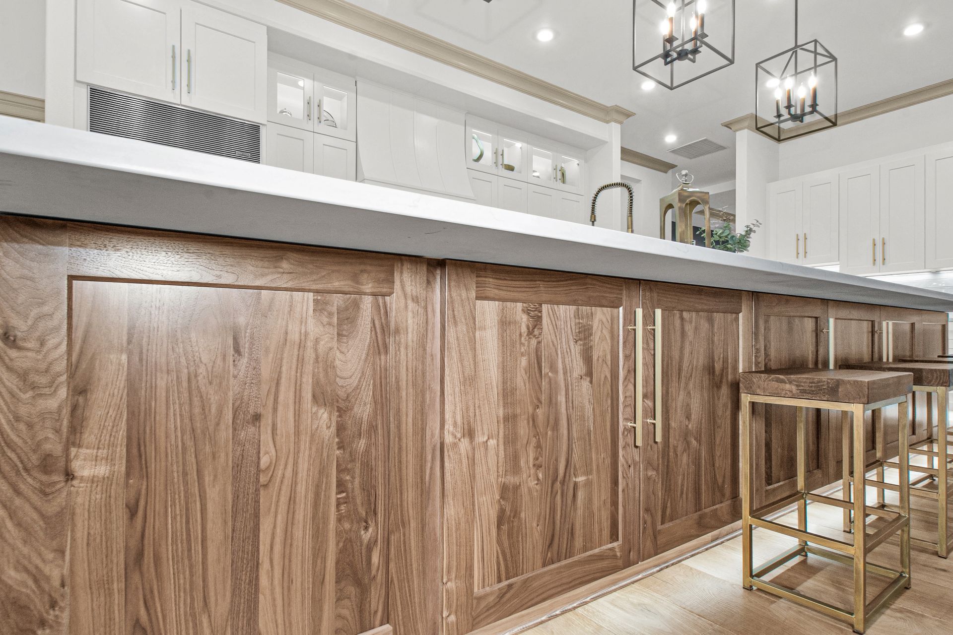 A kitchen with wooden cabinets and stools and a long counter.