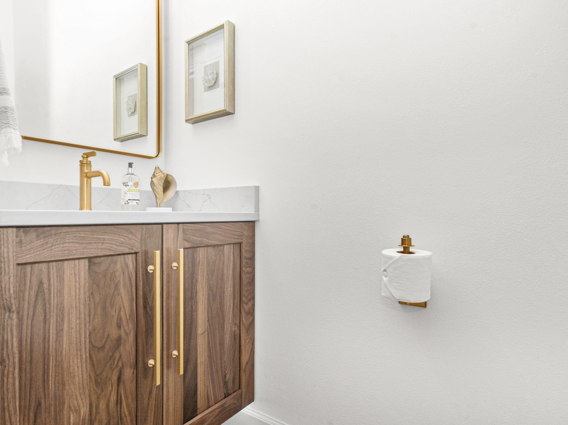 A bathroom with a sink , mirror and toilet paper holder.