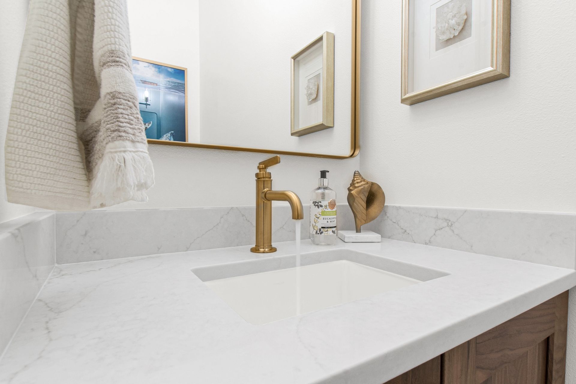 A bathroom with a sink , mirror , and towel hanging on the wall.