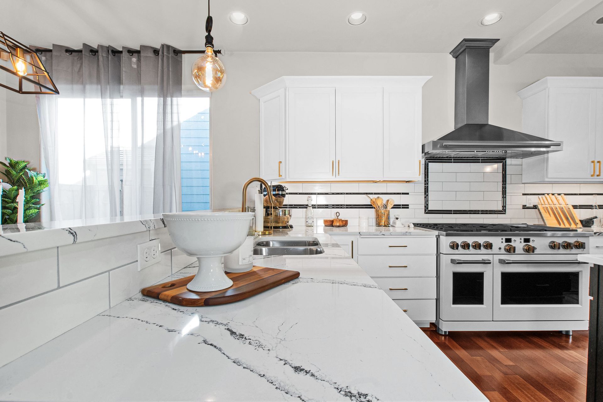A kitchen with white cabinets , stainless steel appliances , a stove and a sink.