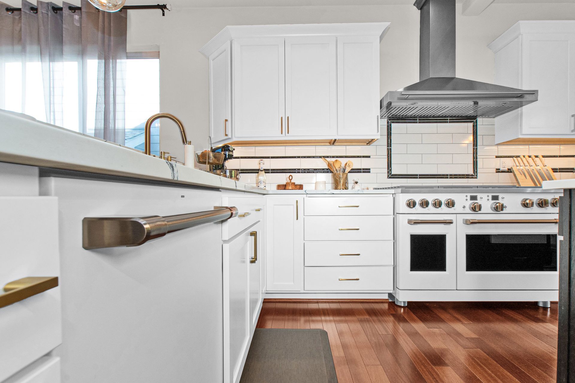 A kitchen with white cabinets , stainless steel appliances , and hardwood floors.