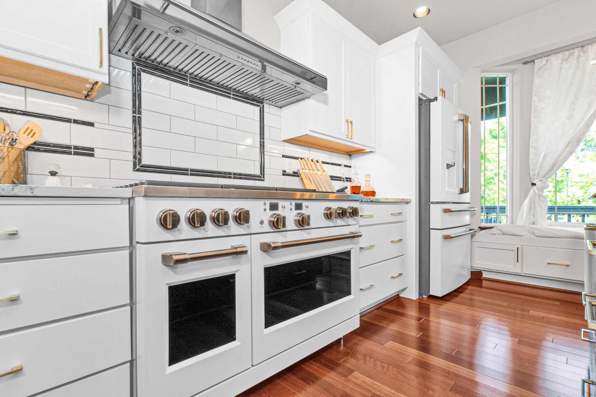 A kitchen with white cabinets , a stove and a refrigerator.