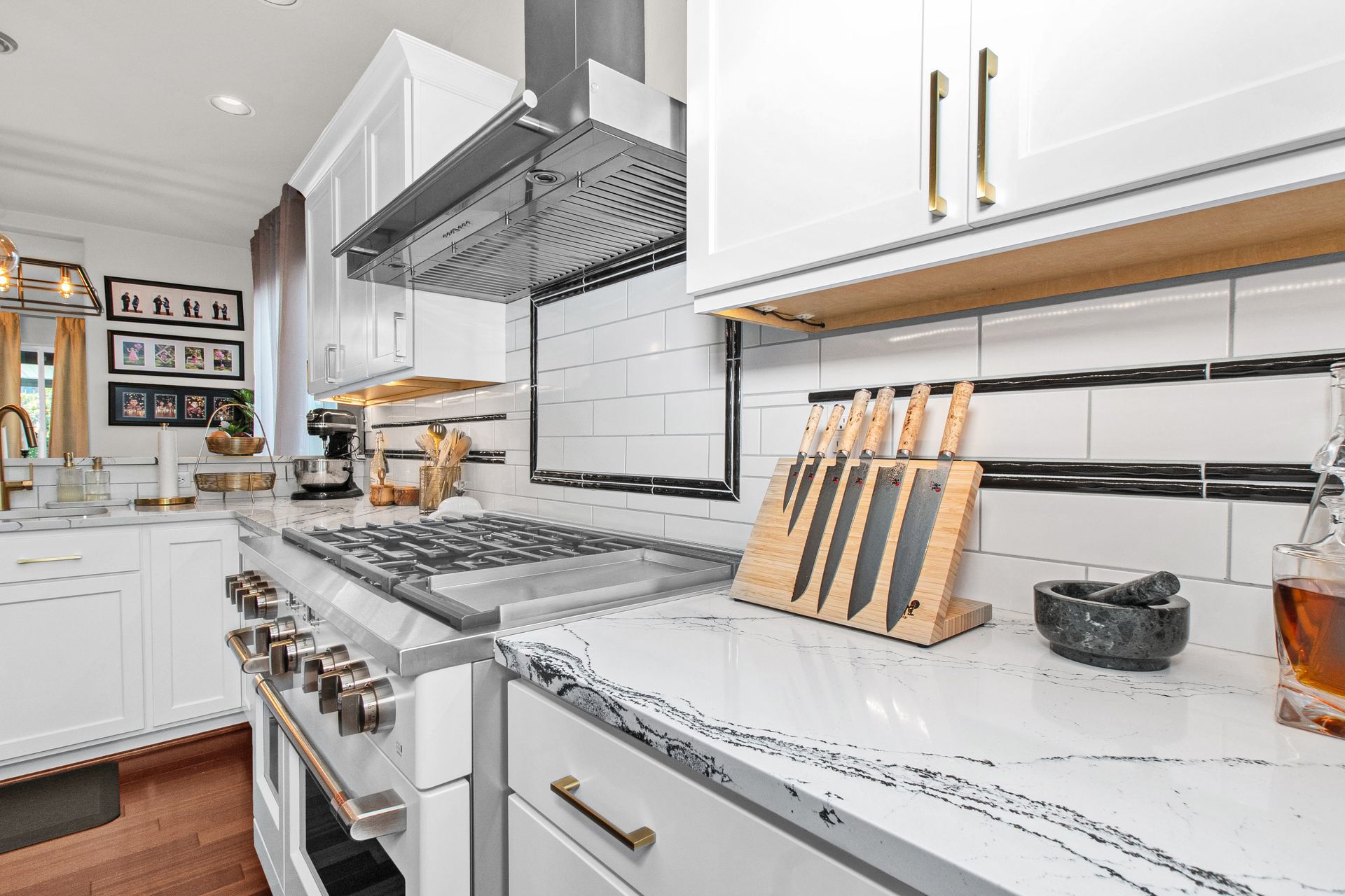 A kitchen with white cabinets , stainless steel appliances , granite counter tops , and a stove top oven.