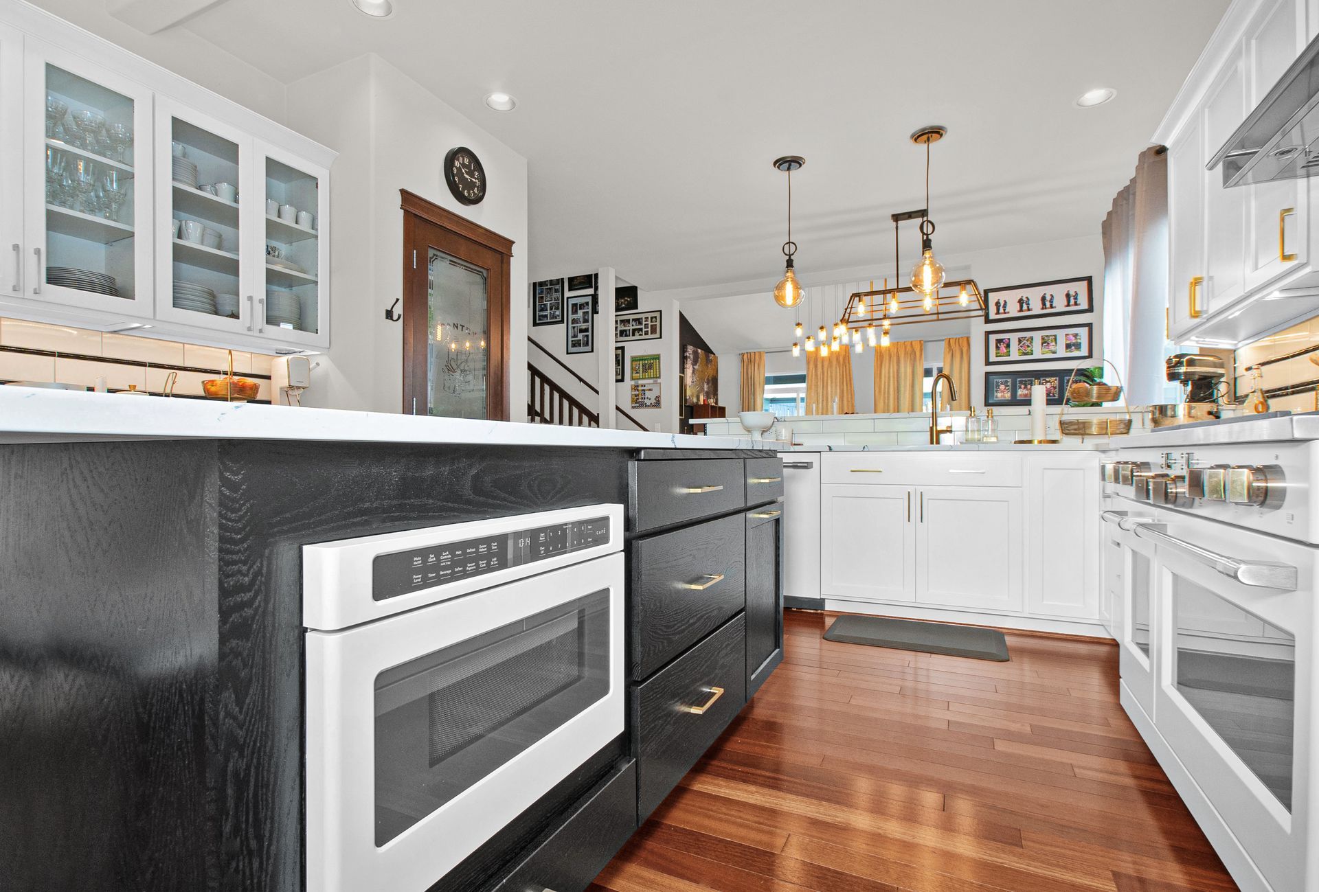 A kitchen with black cabinets and white appliances and a large island.