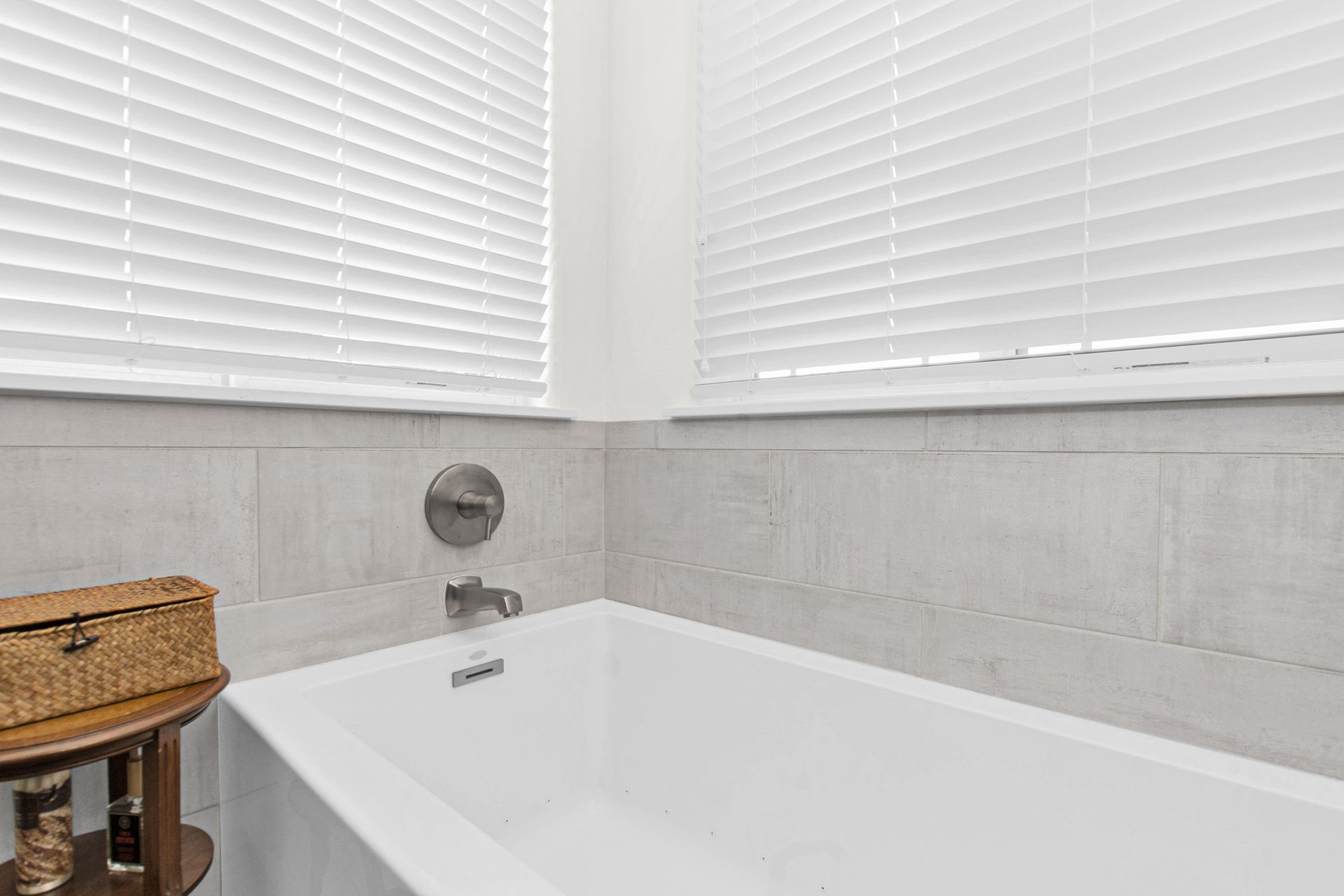 A bathroom with a bathtub and a window with blinds.