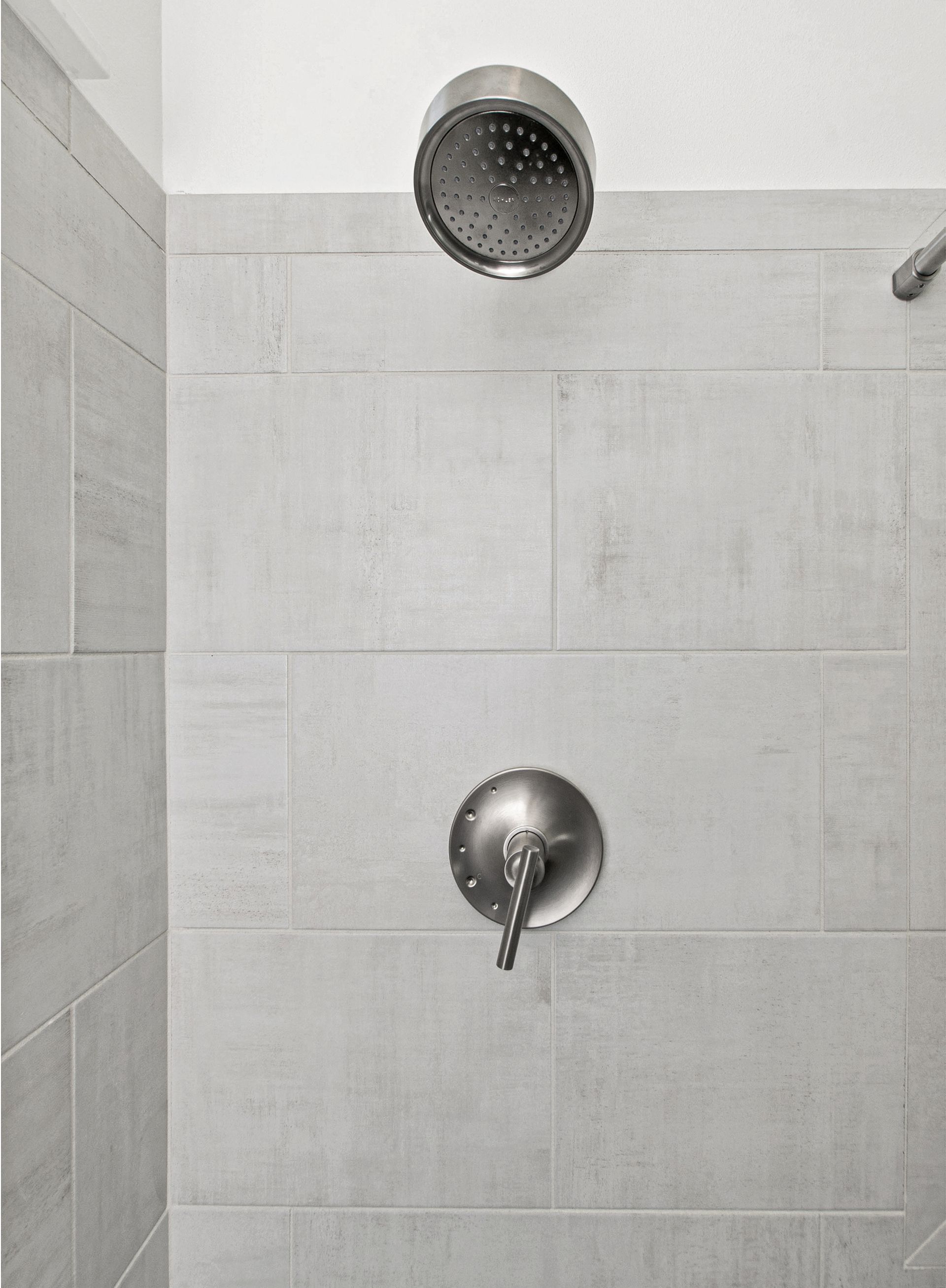 A shower head is hanging from the ceiling in a bathroom.