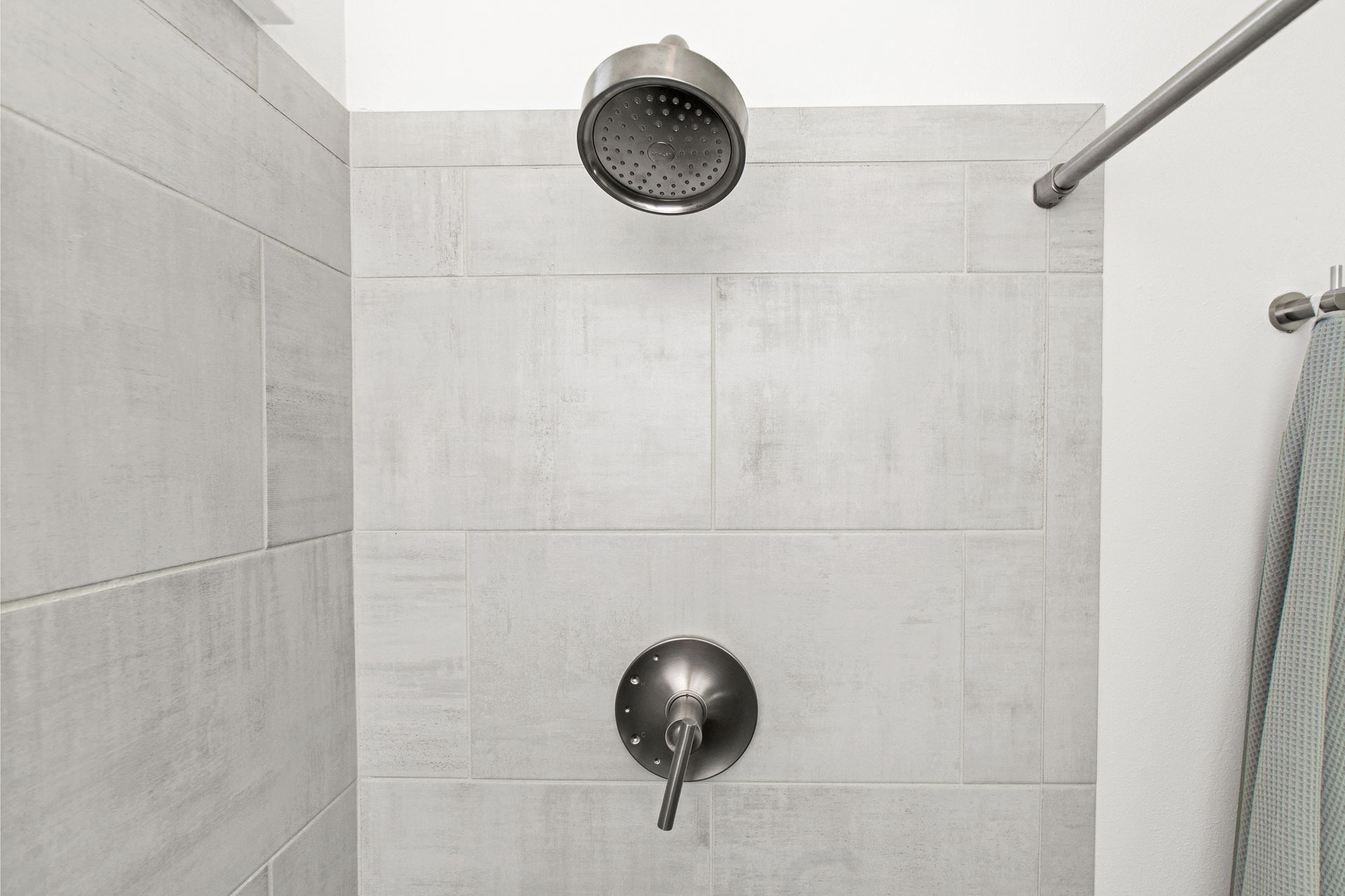 A shower head is hanging from the ceiling in a bathroom.