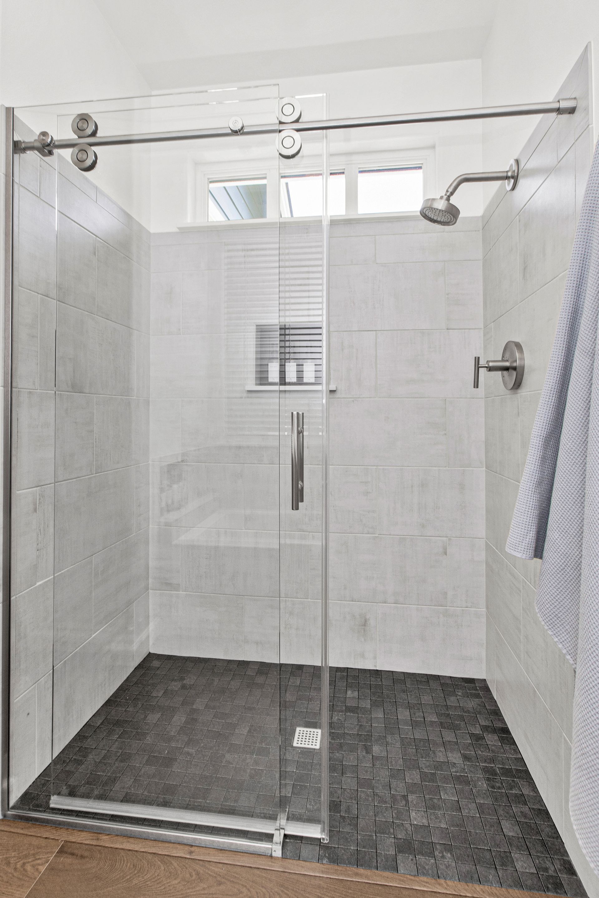 A bathroom with a walk in shower with a sliding glass door.