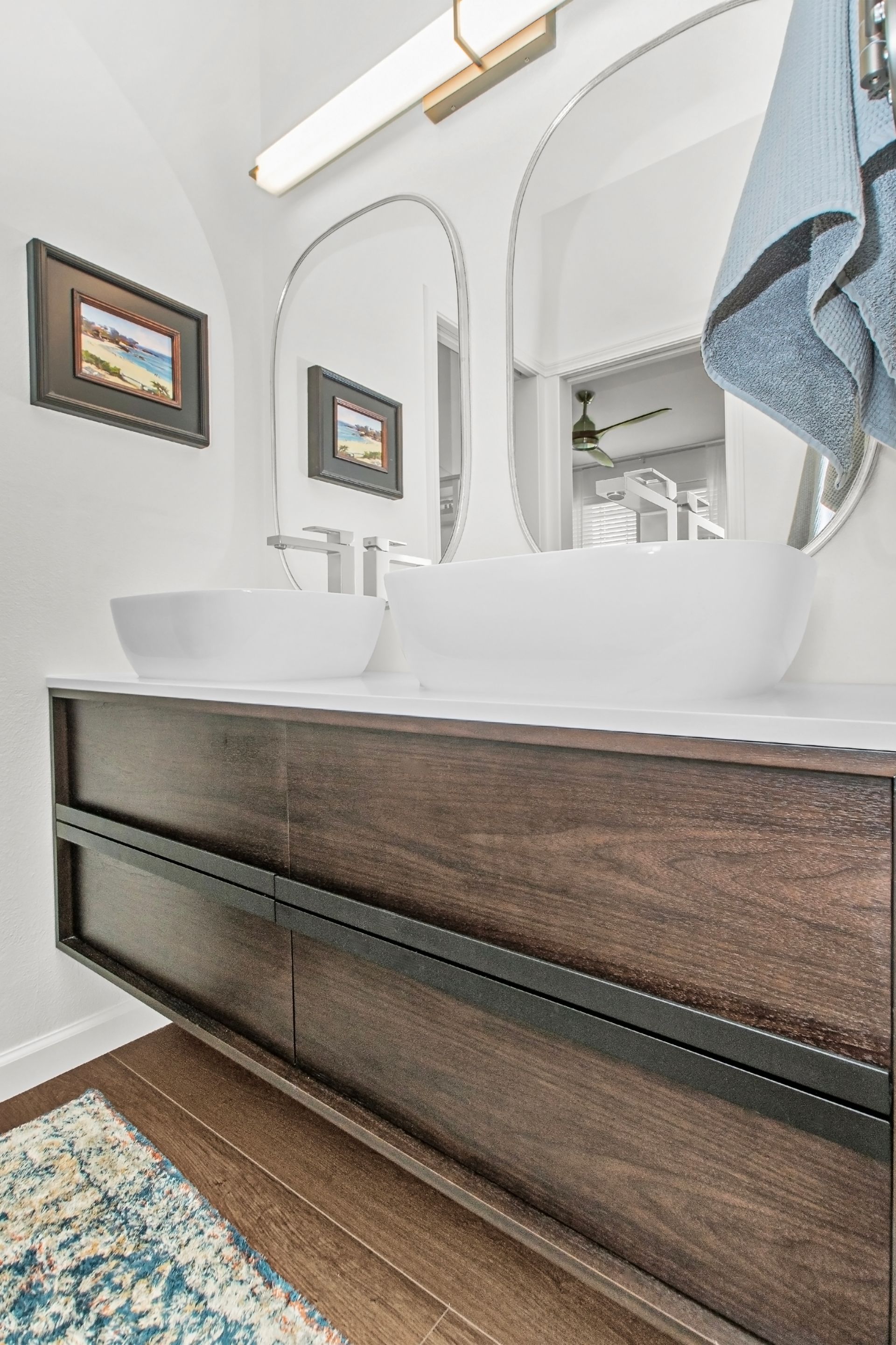 A bathroom with two sinks , a mirror and a rug.