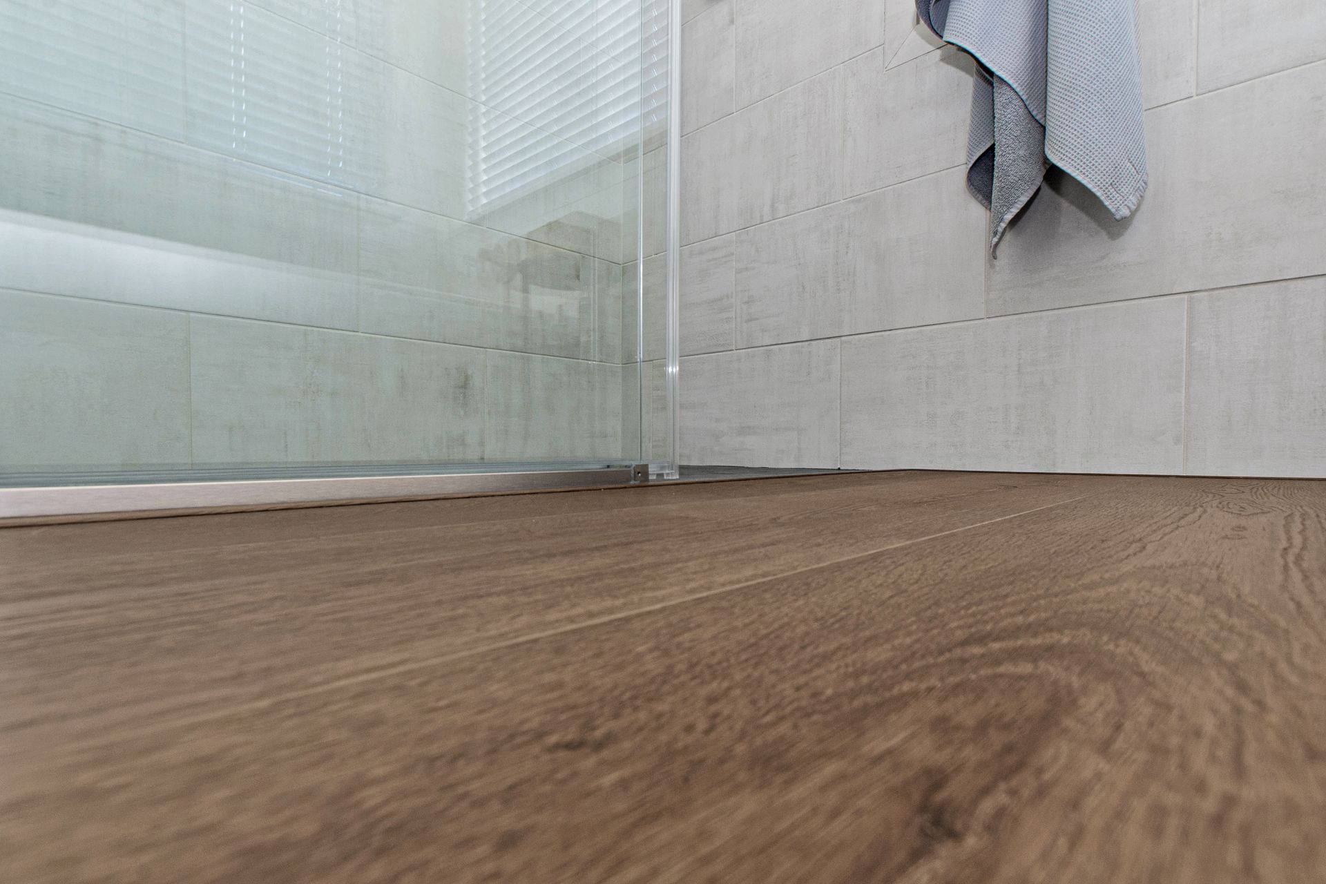 A bathroom with a wooden floor and a glass shower door.