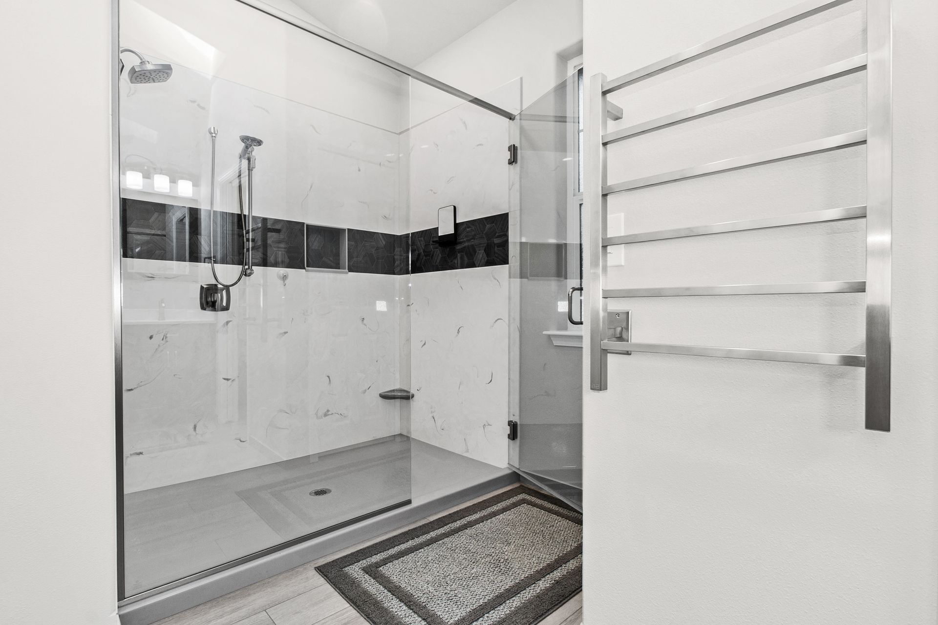 A bathroom with a walk in shower and a towel rack.