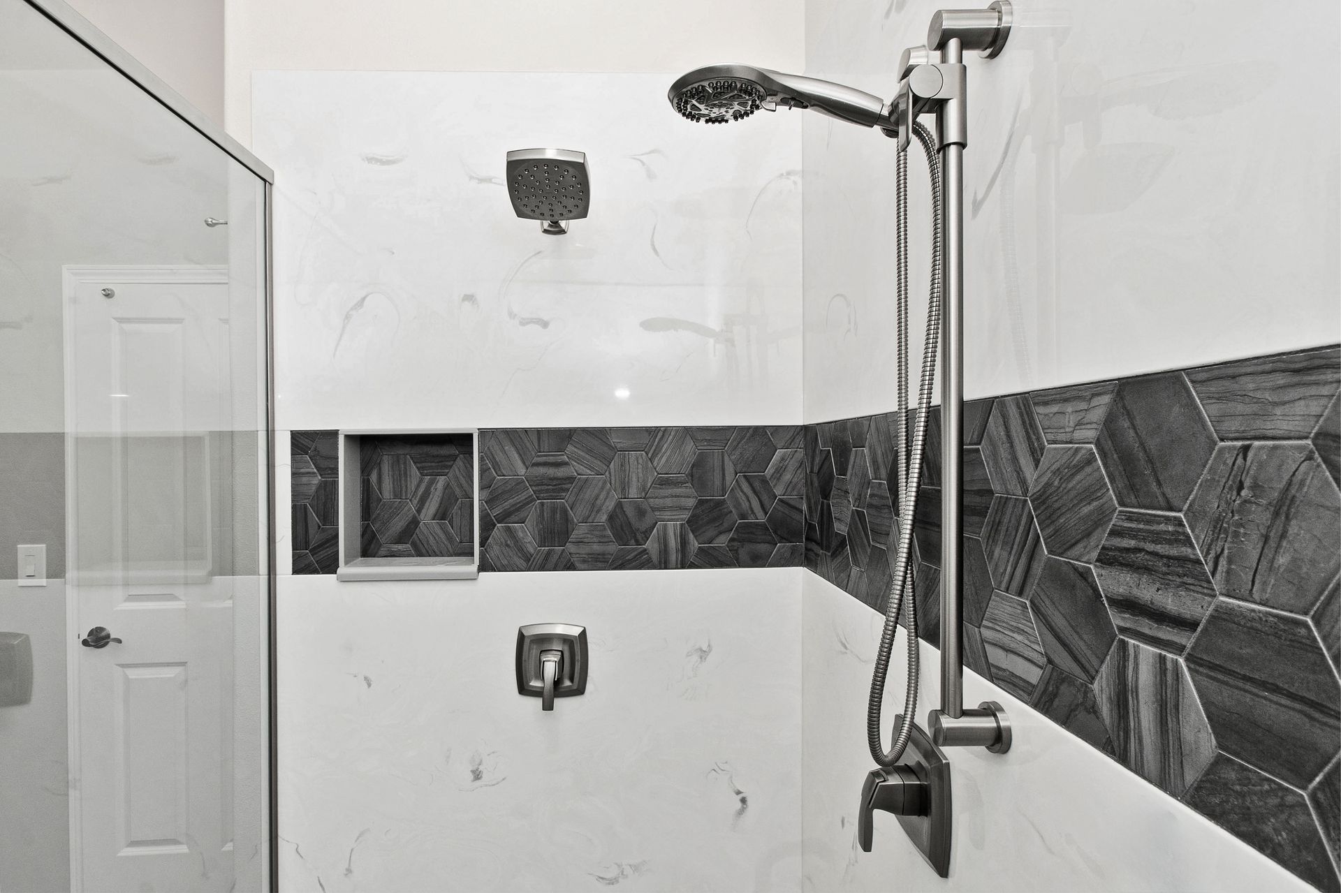 A black and white photo of a shower with a glass door and a shower head.