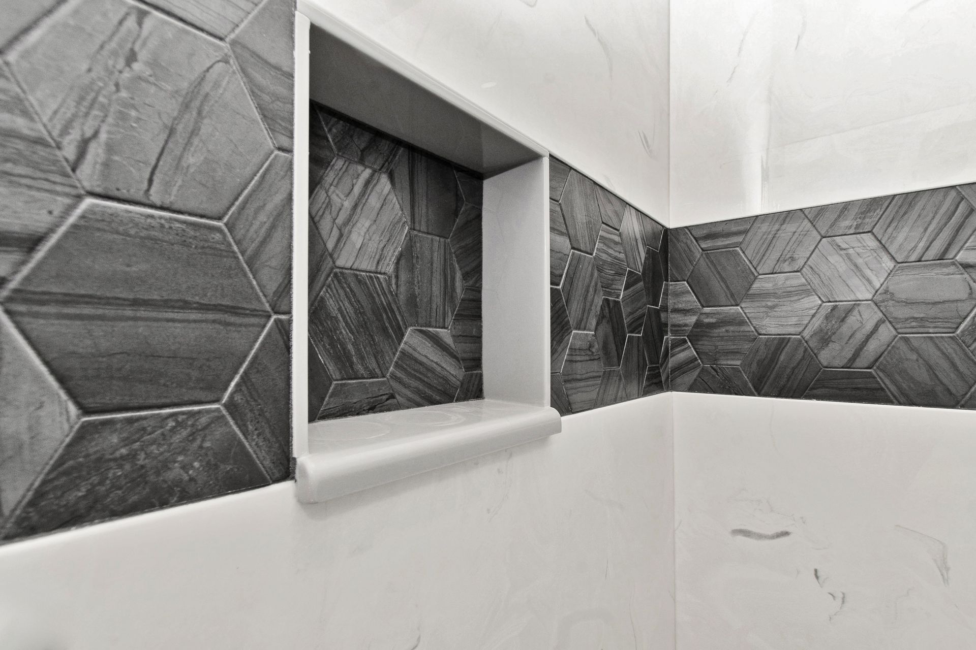 A black and white photo of a bathroom with a shower niche.