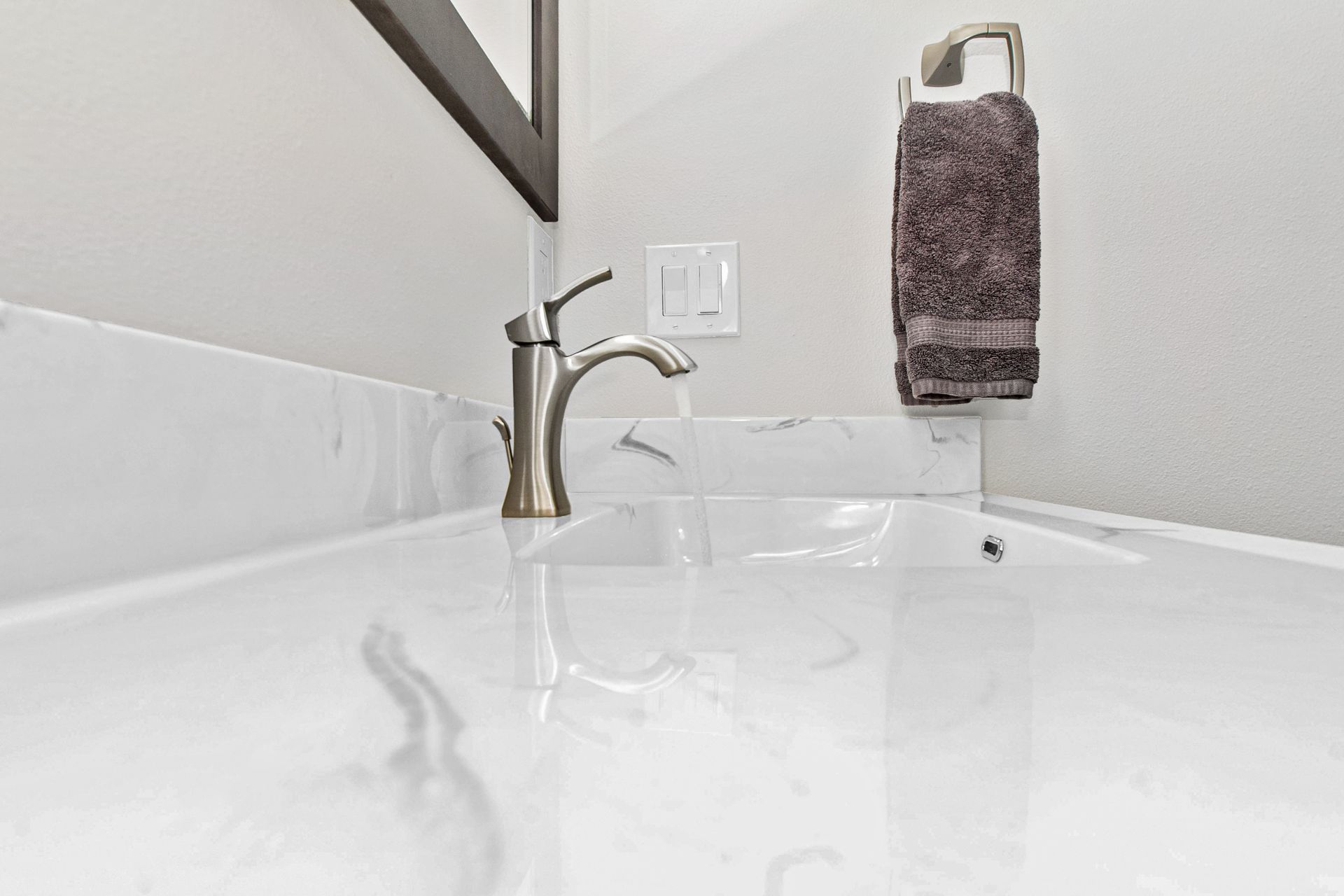 A bathroom sink with a faucet and a towel hanging on the wall.