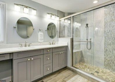 A bathroom with two sinks and a walk in shower.
